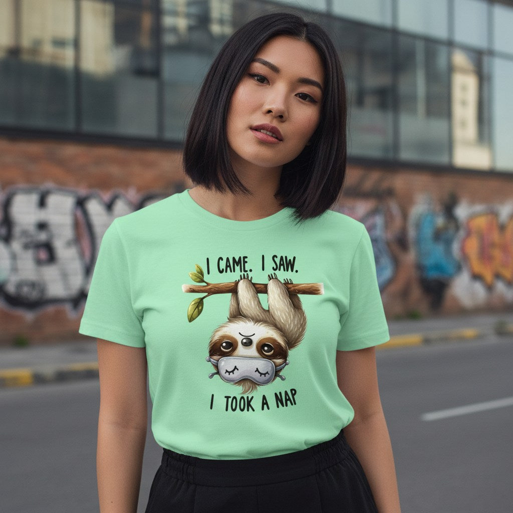 Person wearing a light green t-shirt with a sloth graphic and text in an urban setting.