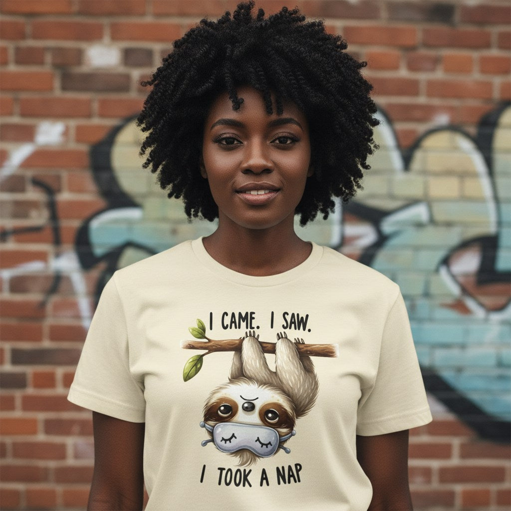 Person wearing a t-shirt with a sloth graphic and text in front of a graffiti-covered wall.