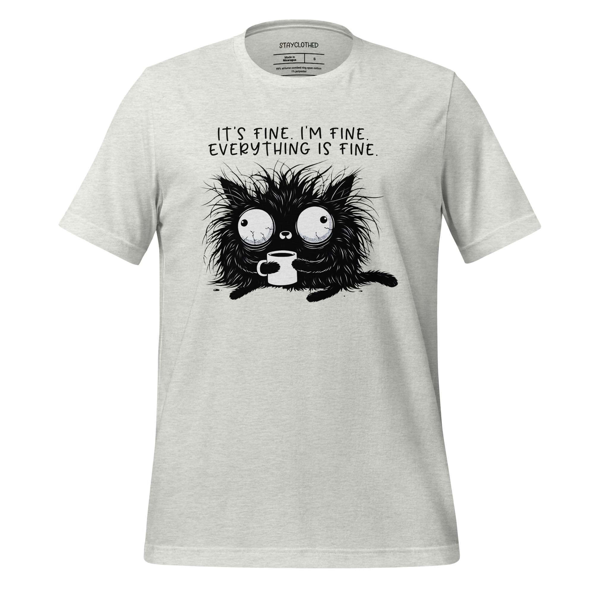 White t-shirt with a black cat graphic and text on a wooden surface, featuring the brand 'StayClothed'.