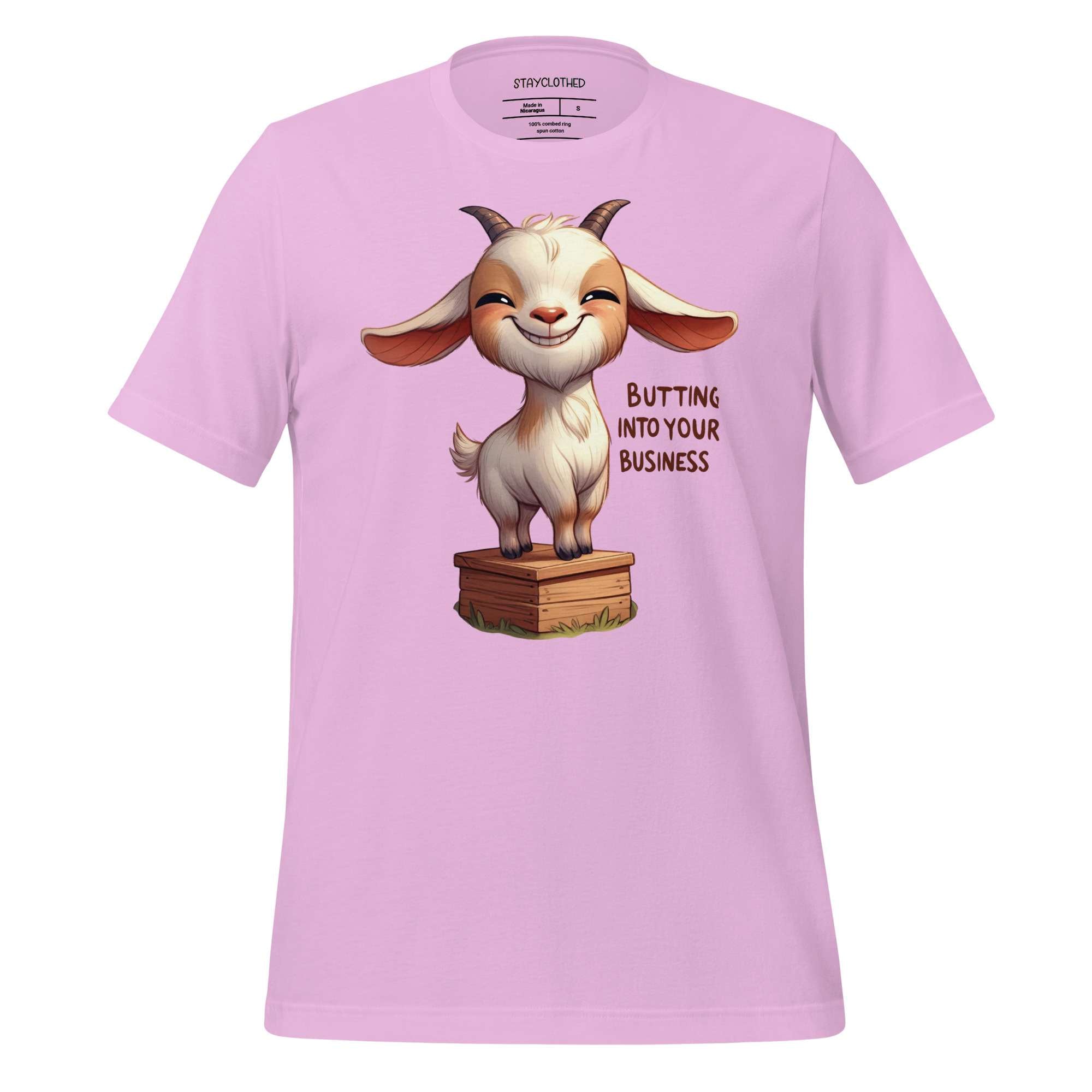 Pink t-shirt with a cartoon goat graphic and text on a wooden surface, featuring the brand 'StayClothed'.