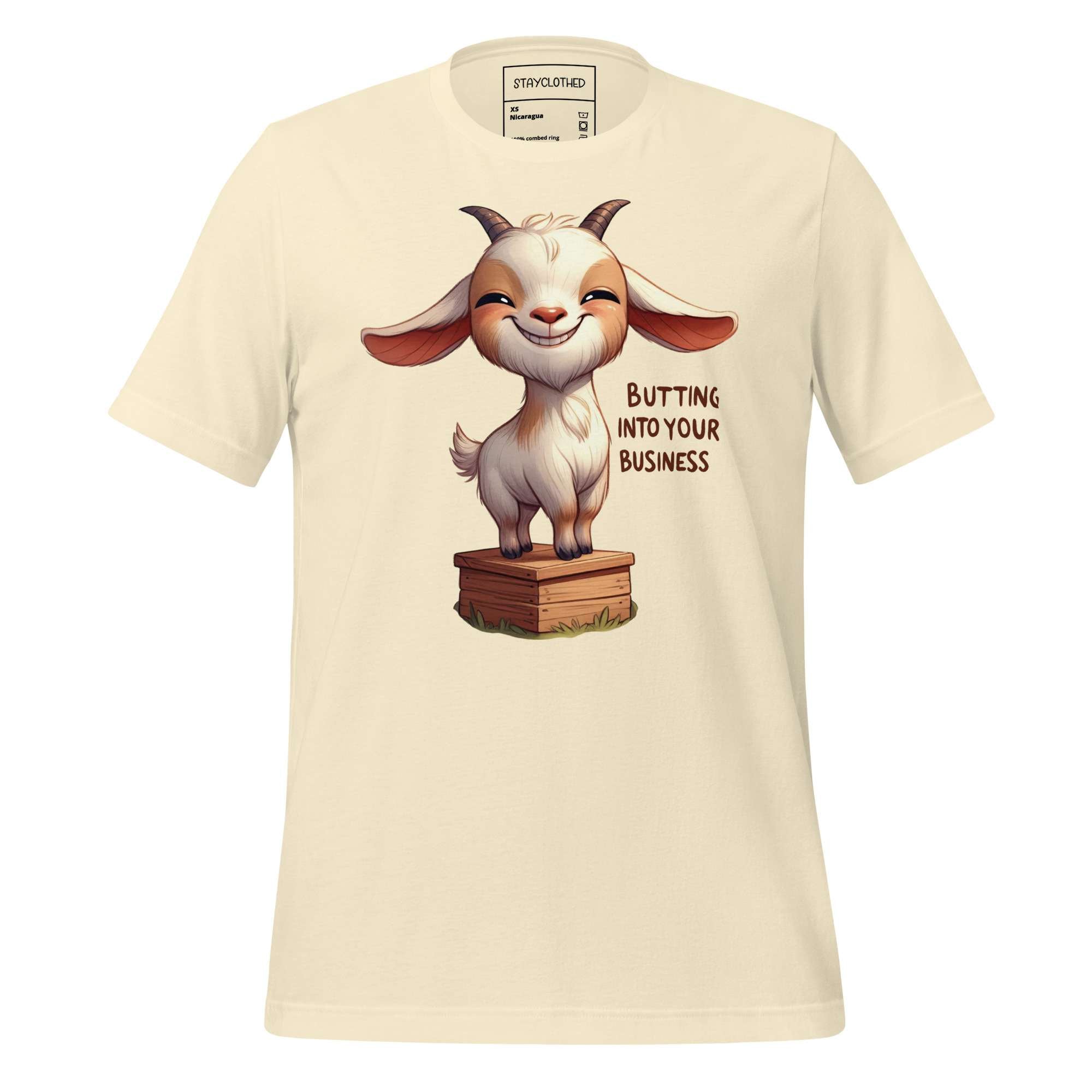 Beige t-shirt with a cartoon goat graphic and text on a wooden surface, featuring the brand 'StayClothed'.