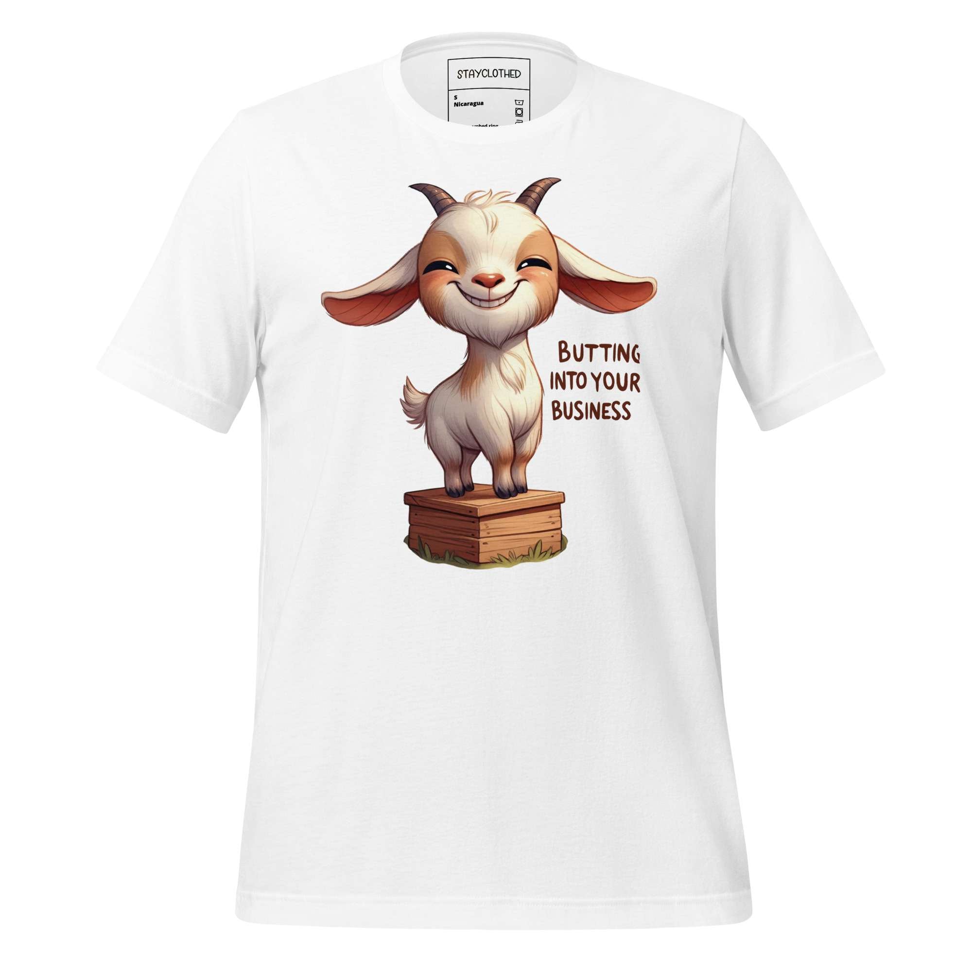 White t-shirt with a cartoon goat graphic and text on a wooden surface, featuring the brand 'StayClothed'.