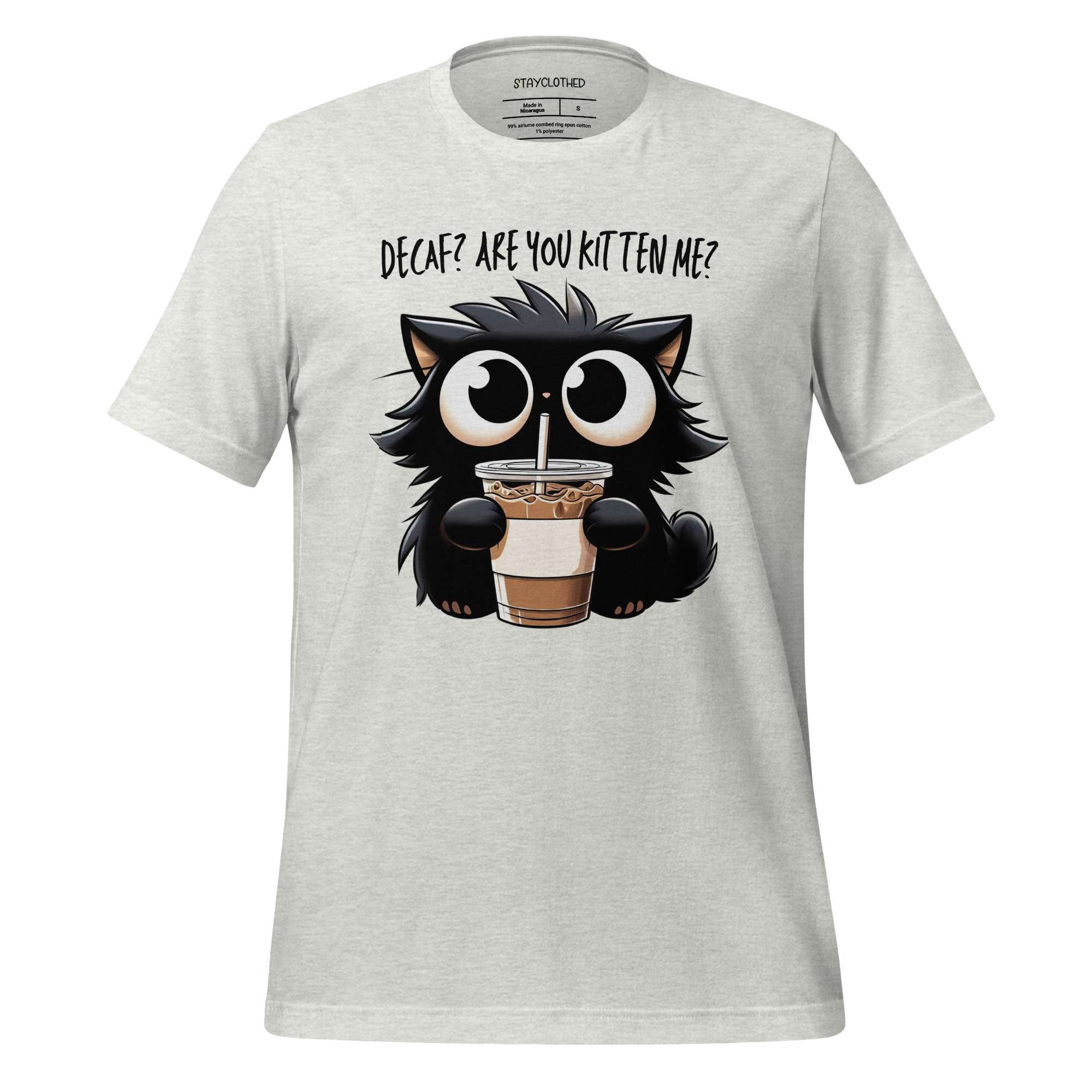 White t-shirt with a cartoon cat holding a coffee cup on a wooden background, featuring the brand 'StayClothed'.