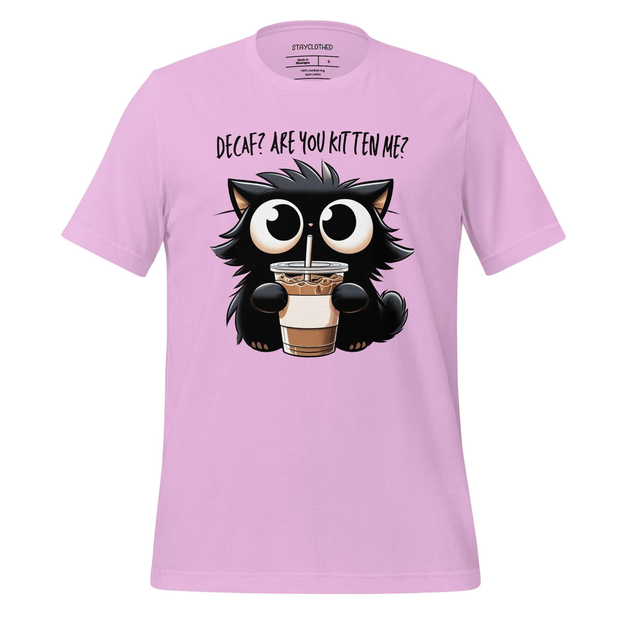 Pink t-shirt with a cat holding a drink graphic on a wooden surface, featuring the brand 'StayClothed'.