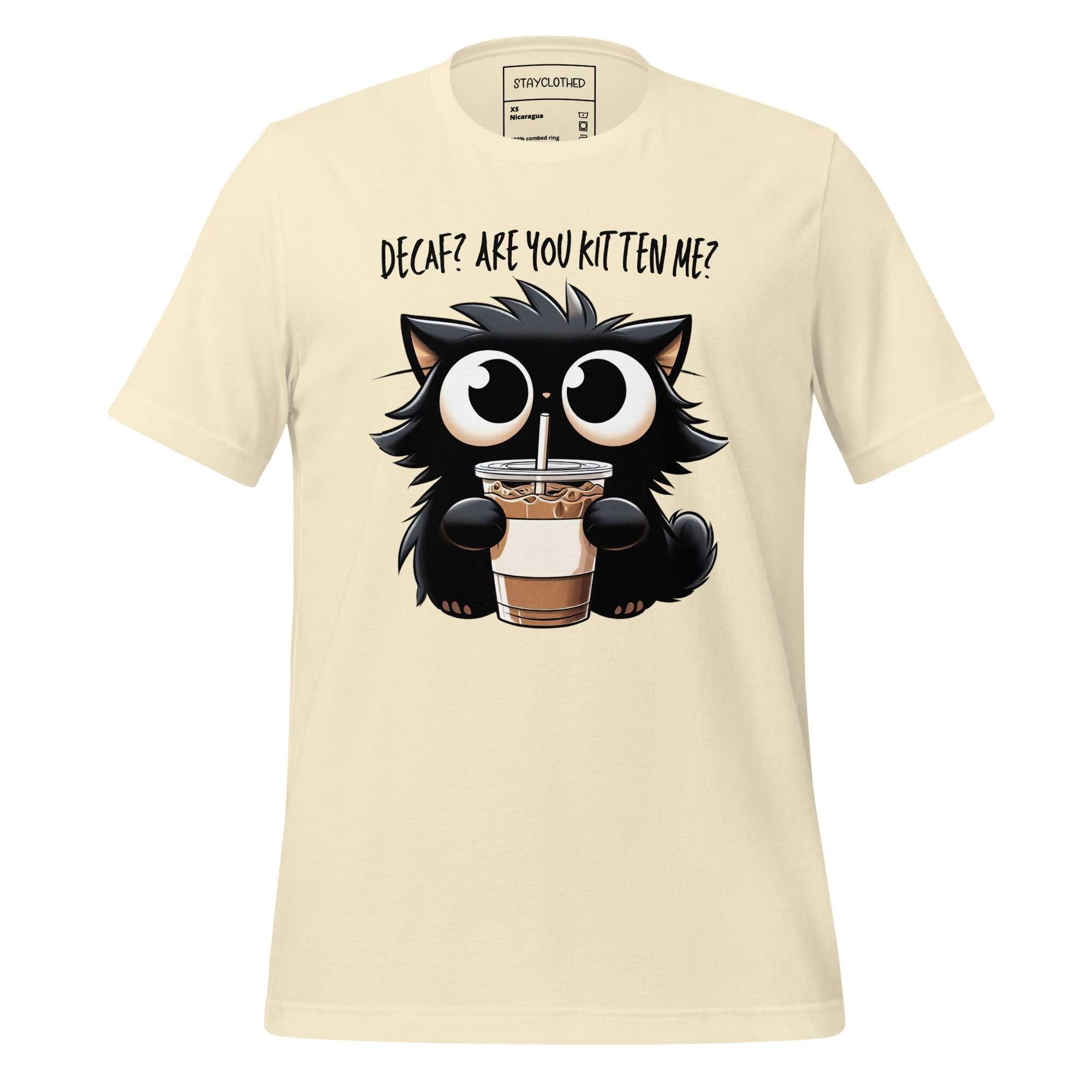 Beige t-shirt with a cat holding a drink graphic on a wooden surface, featuring the brand 'StayClothed'.