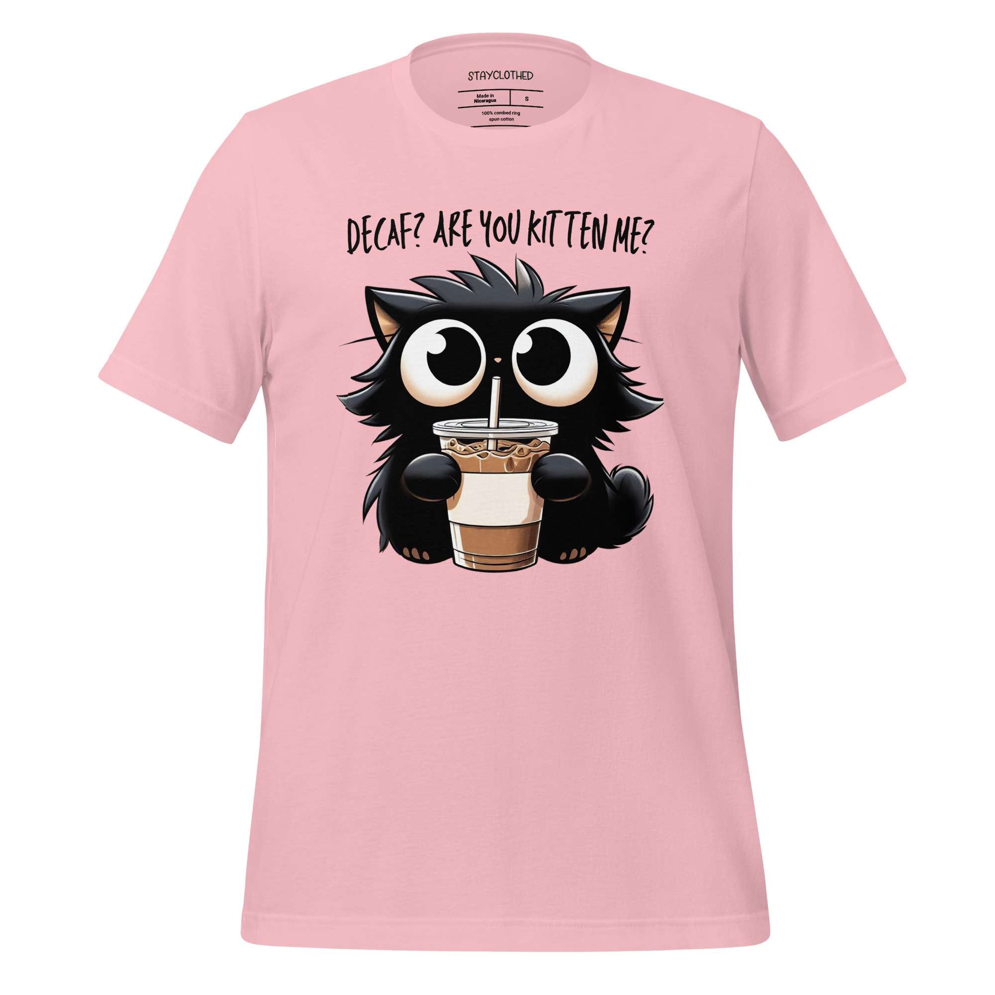 Pink t-shirt with a cat holding a coffee cup graphic on a wooden surface, featuring the brand 'StayClothed'.