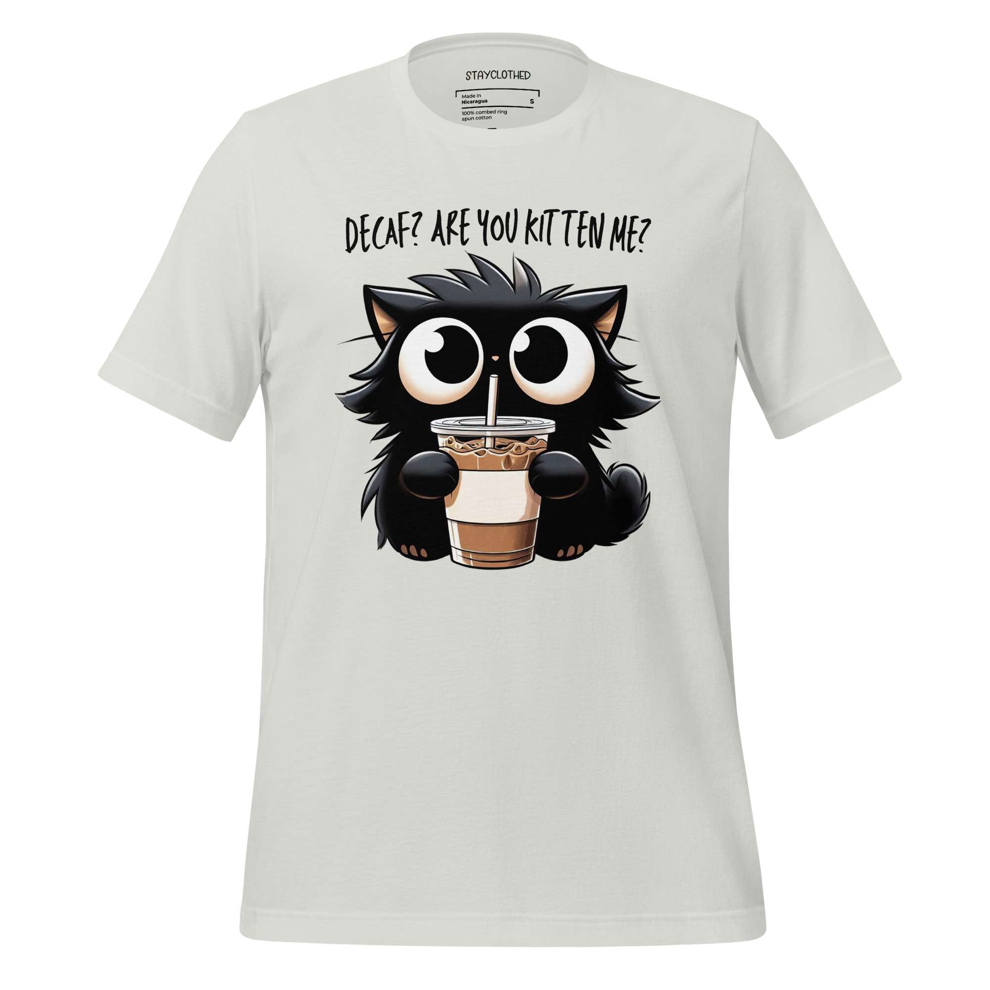 White t-shirt with a cartoon cat holding a coffee cup on a wooden surface, featuring the brand 'StayClothed'.