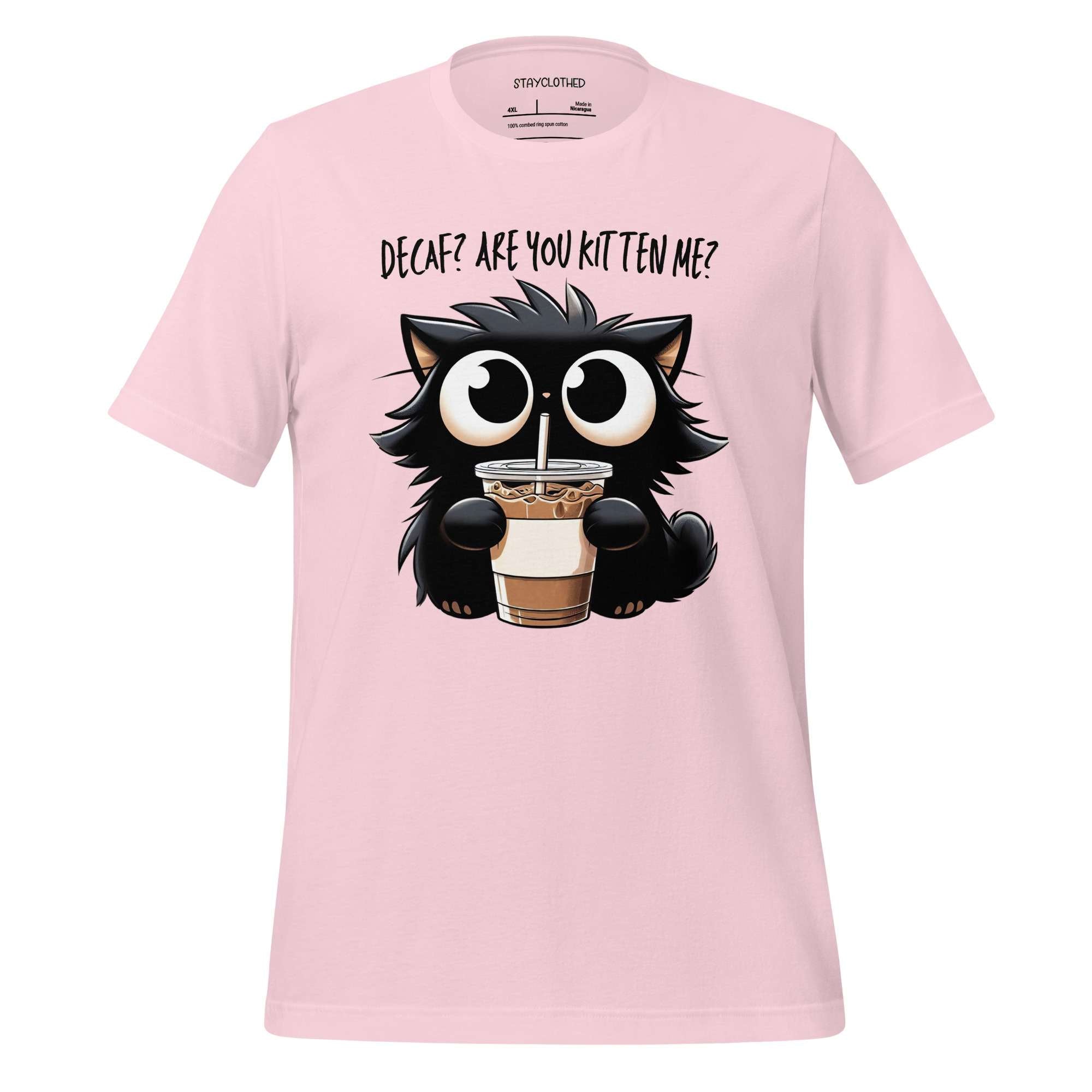 Pink t-shirt with a cat holding a coffee cup graphic on a wooden surface, featuring the brand 'StayClothed'.