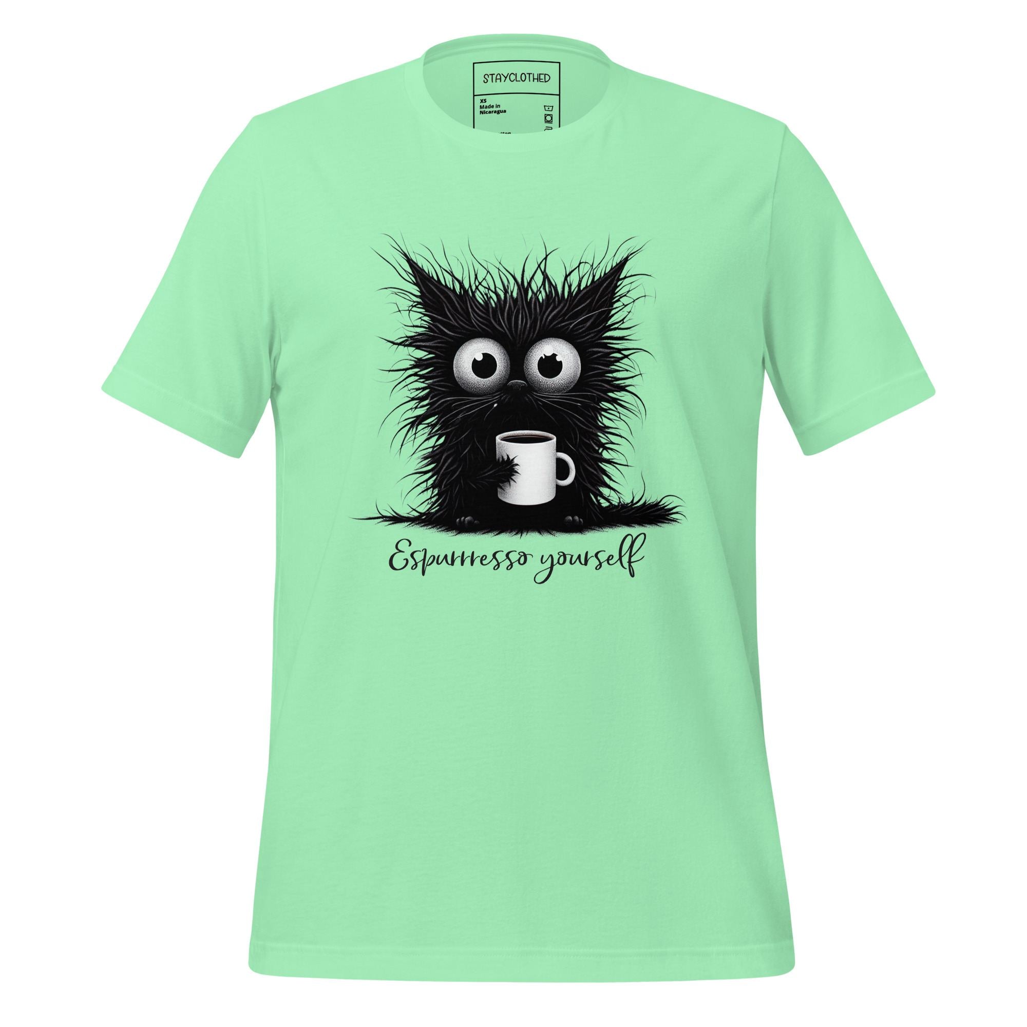 Light green t-shirt with a black cat graphic and 'Espressesso yourself' text on a wooden surface, branded 'StayClothed'.