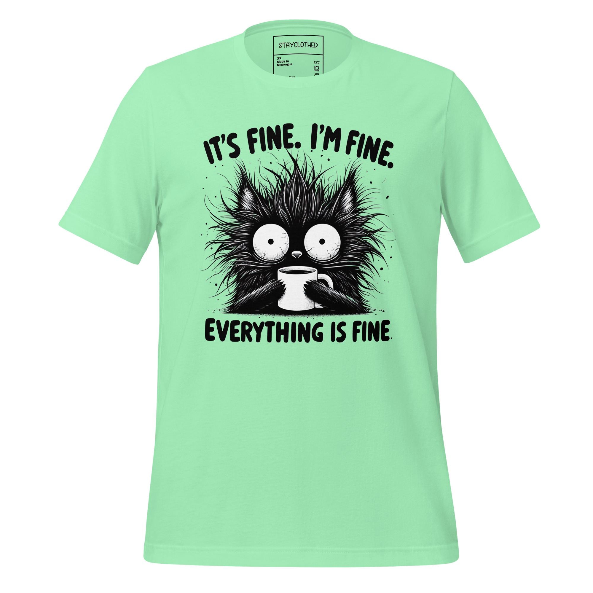 Mint green t-shirt with a black cat graphic and text on a wooden surface, featuring the brand 'StayClothed'.