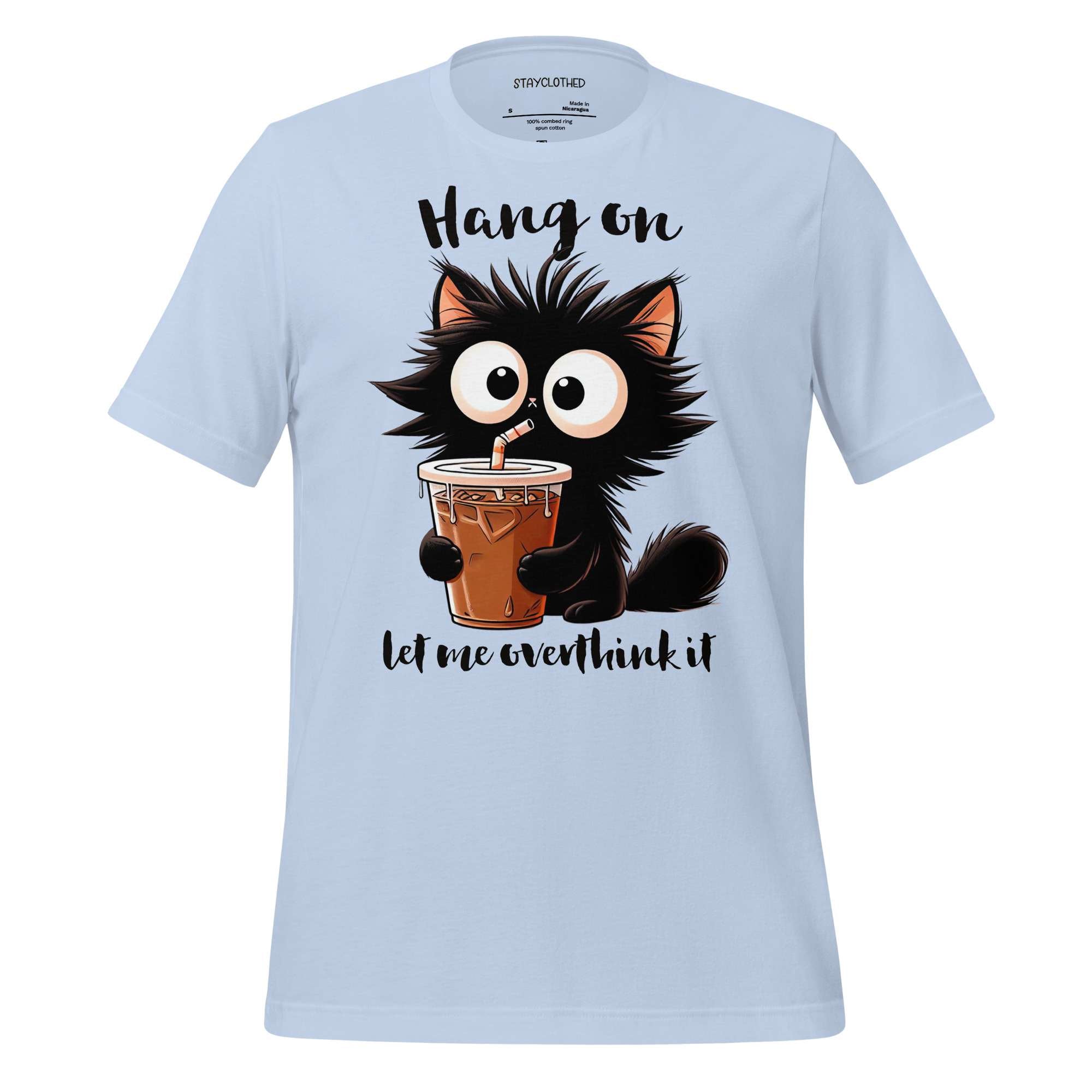 White t-shirt with a cartoon cat holding a drink on a wooden surface, featuring the brand 'StayClothed'.