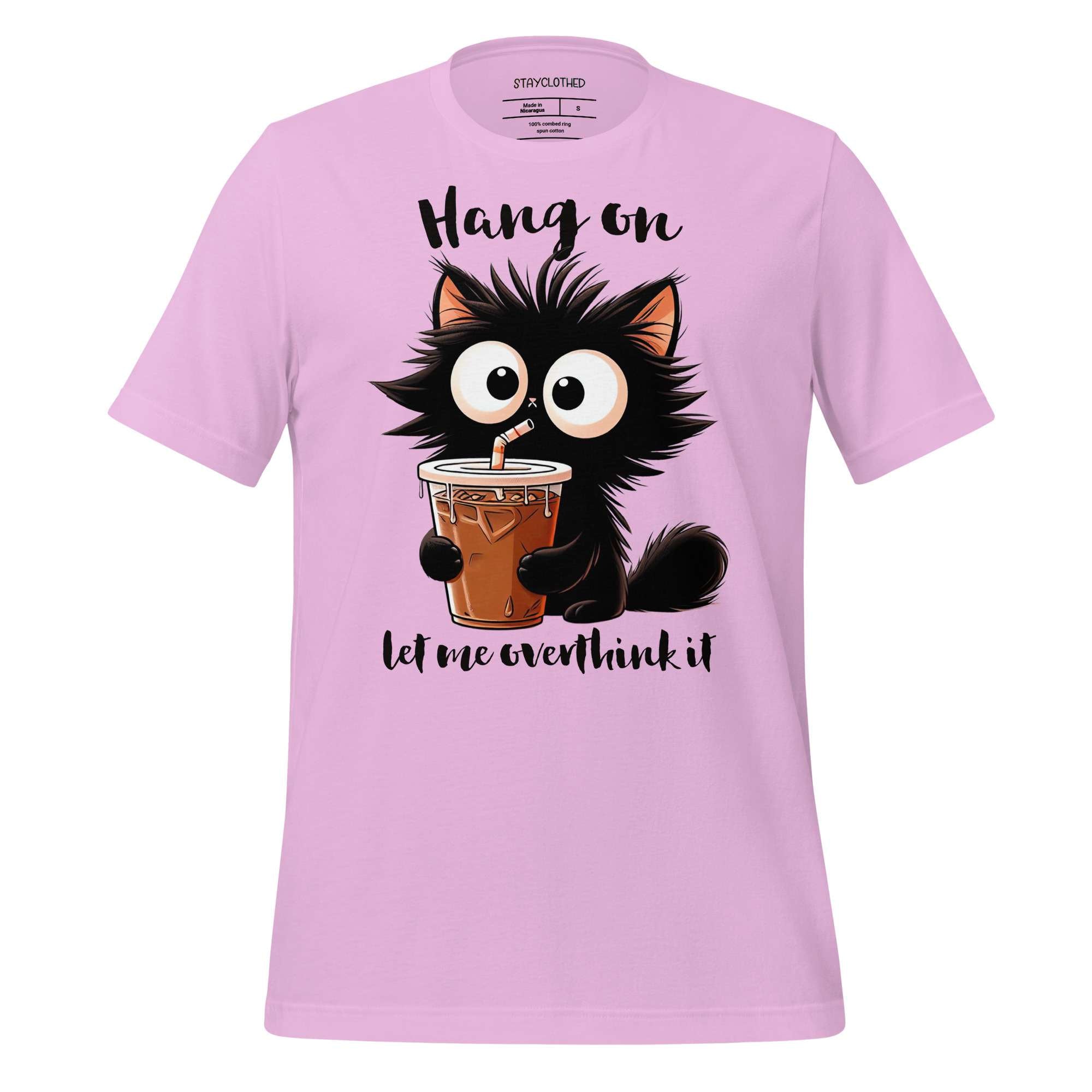 Pink t-shirt with a cartoon cat holding a drink on a wooden surface, featuring the brand 'StayClothed'.