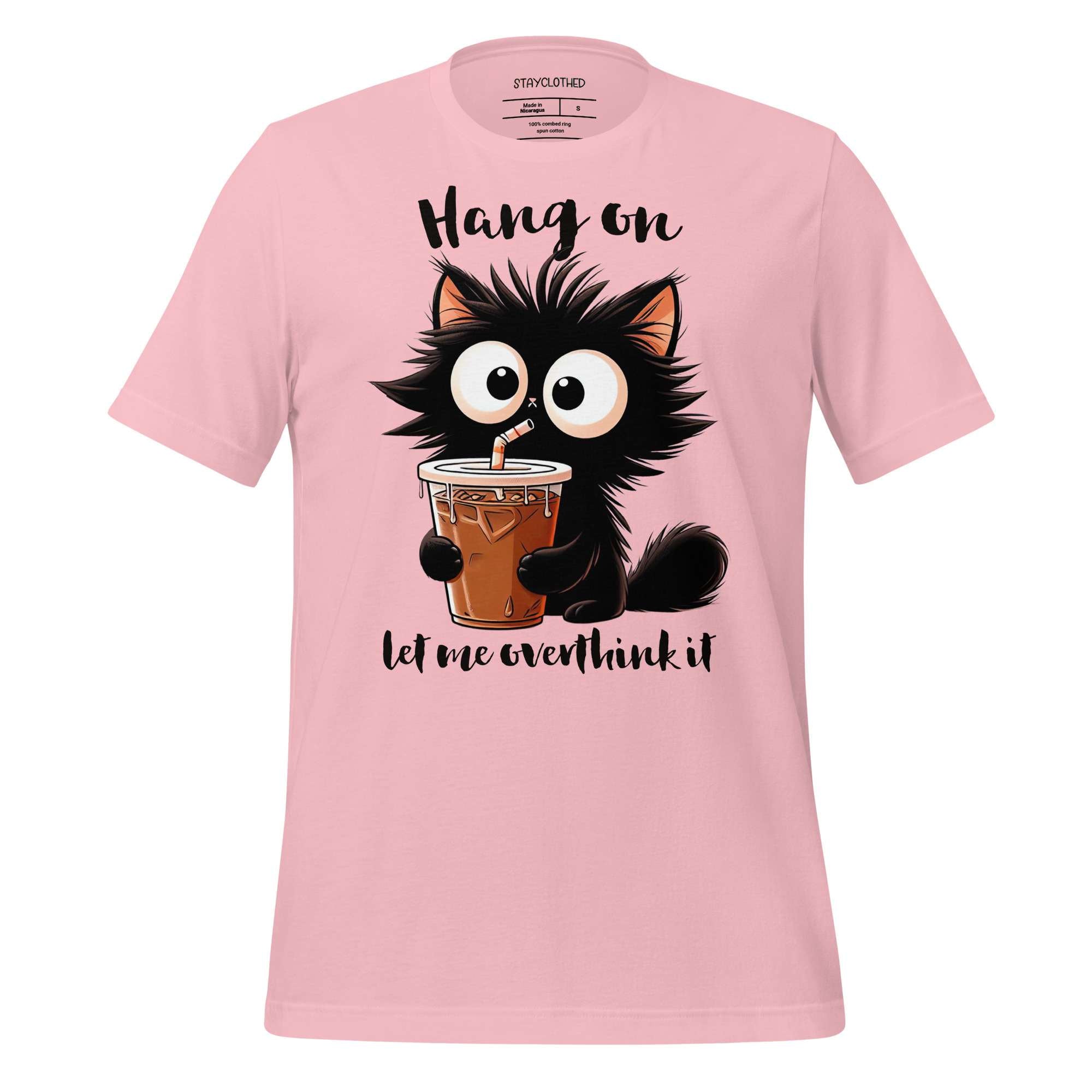 Pink t-shirt with a cartoon cat holding a drink on a wooden surface, featuring the brand 'StayClothed'.