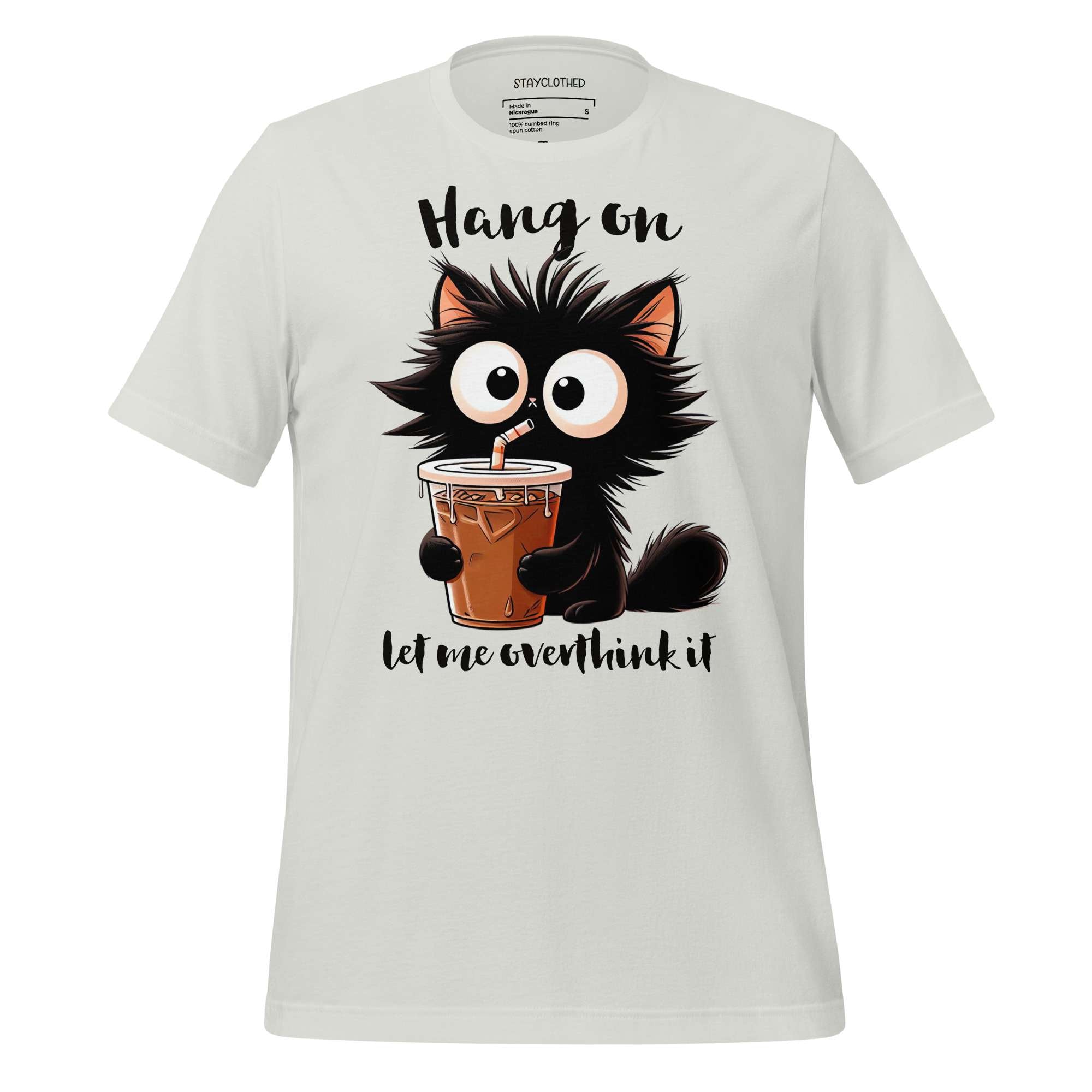 White t-shirt with a cartoon cat holding a drink on a wooden surface, featuring the brand 'StayClothed'.