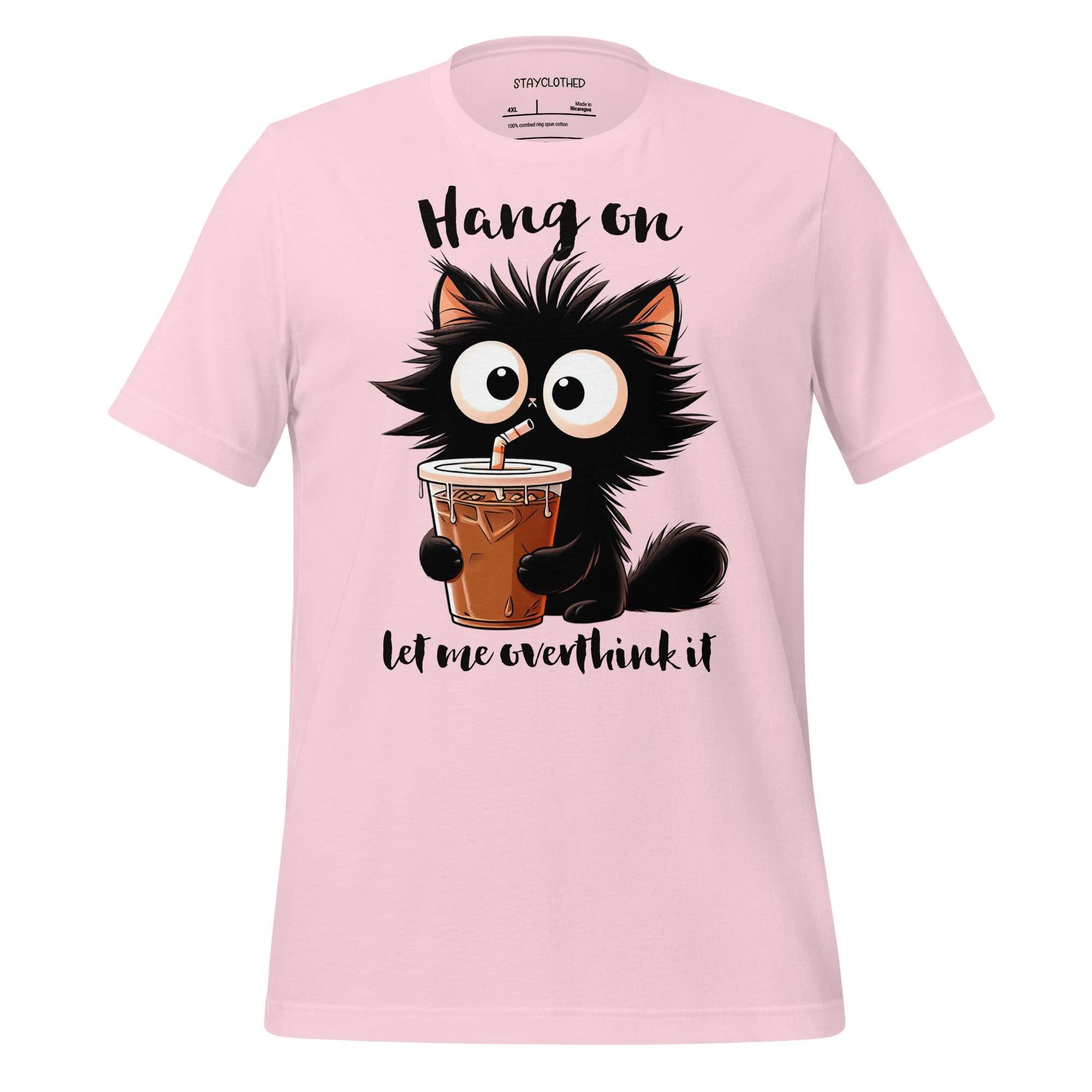 Pink t-shirt with a cartoon cat holding a drink on a wooden surface, featuring the brand 'StayClothed'.