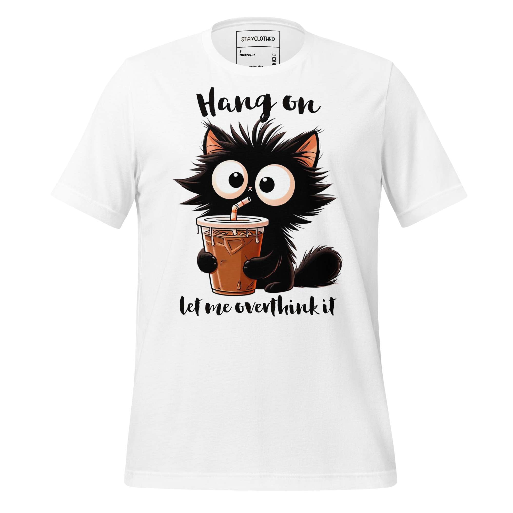 White t-shirt with a cartoon cat holding a drink on a wooden surface, featuring the brand 'StayClothed'.