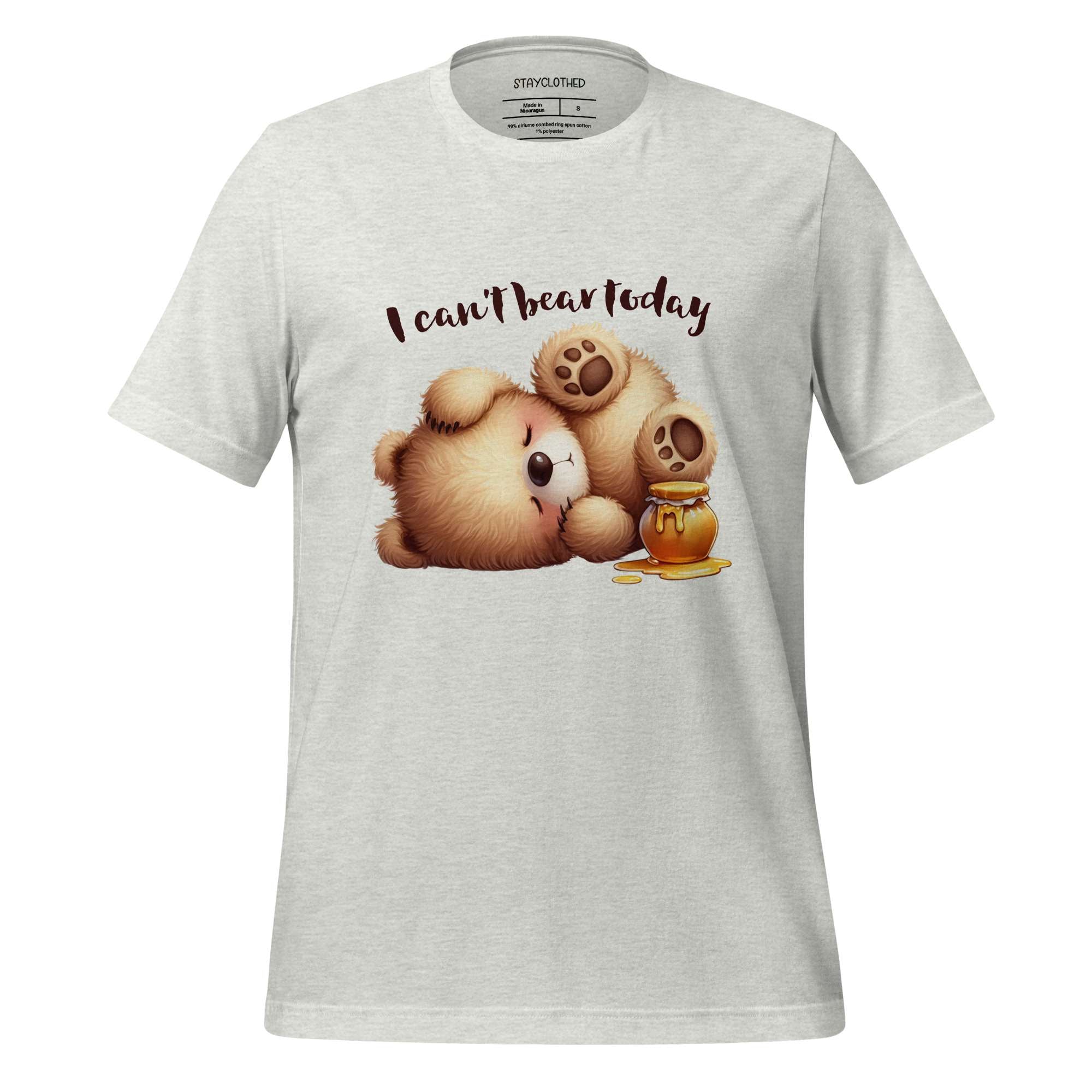 White t-shirt with teddy bear graphic and text 'I can't bear today' on a wooden surface, featuring the brand 'StayClothed'.