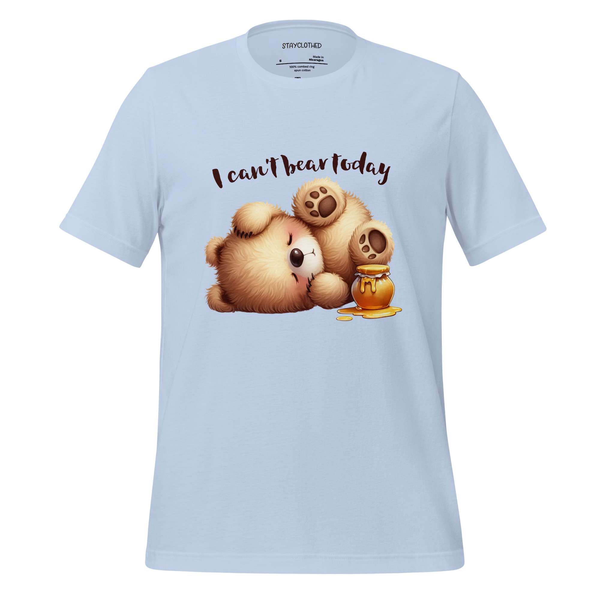 White t-shirt with cartoon bear and honey design on a wooden surface, featuring 'StayClothed' brand.