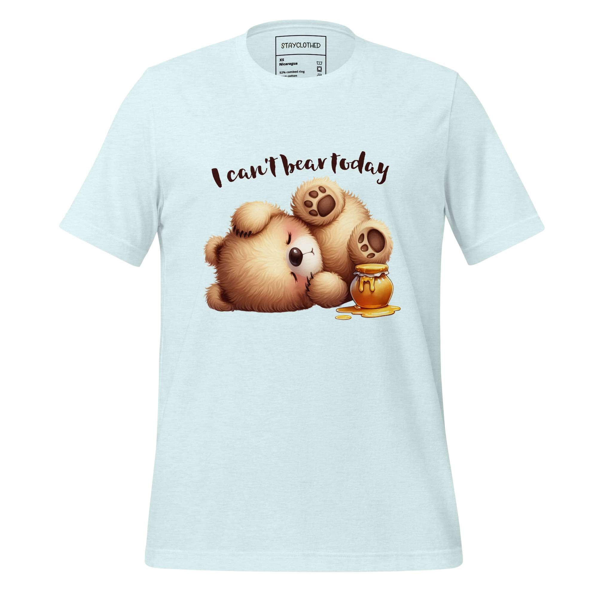 White t-shirt with teddy bear graphic and text 'I can't bear today' on a wooden surface, featuring the brand 'StayClothed'.