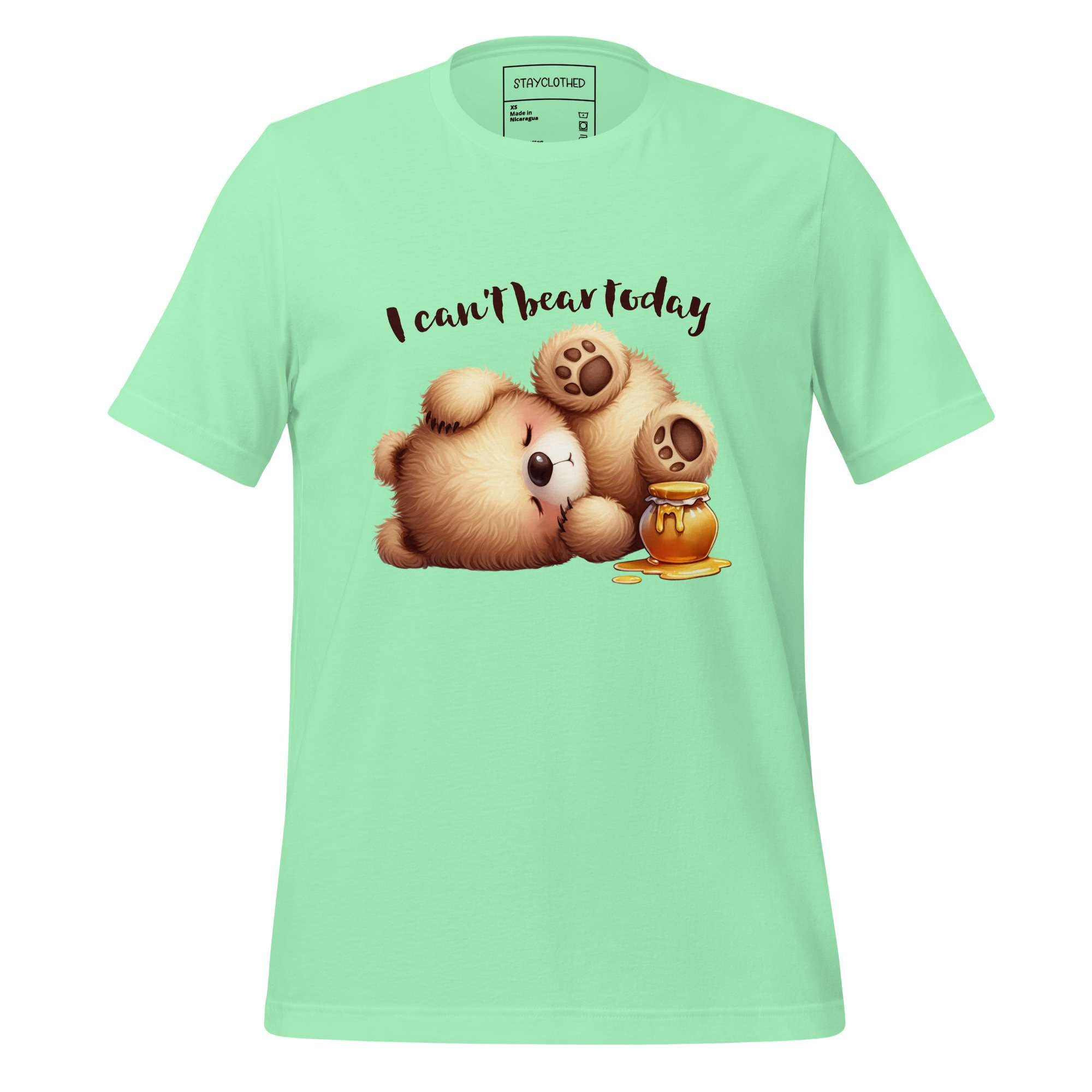 Light green t-shirt with cartoon bear design and text 'I can't bear today' on a wooden surface, featuring the brand 'StayClothed'.