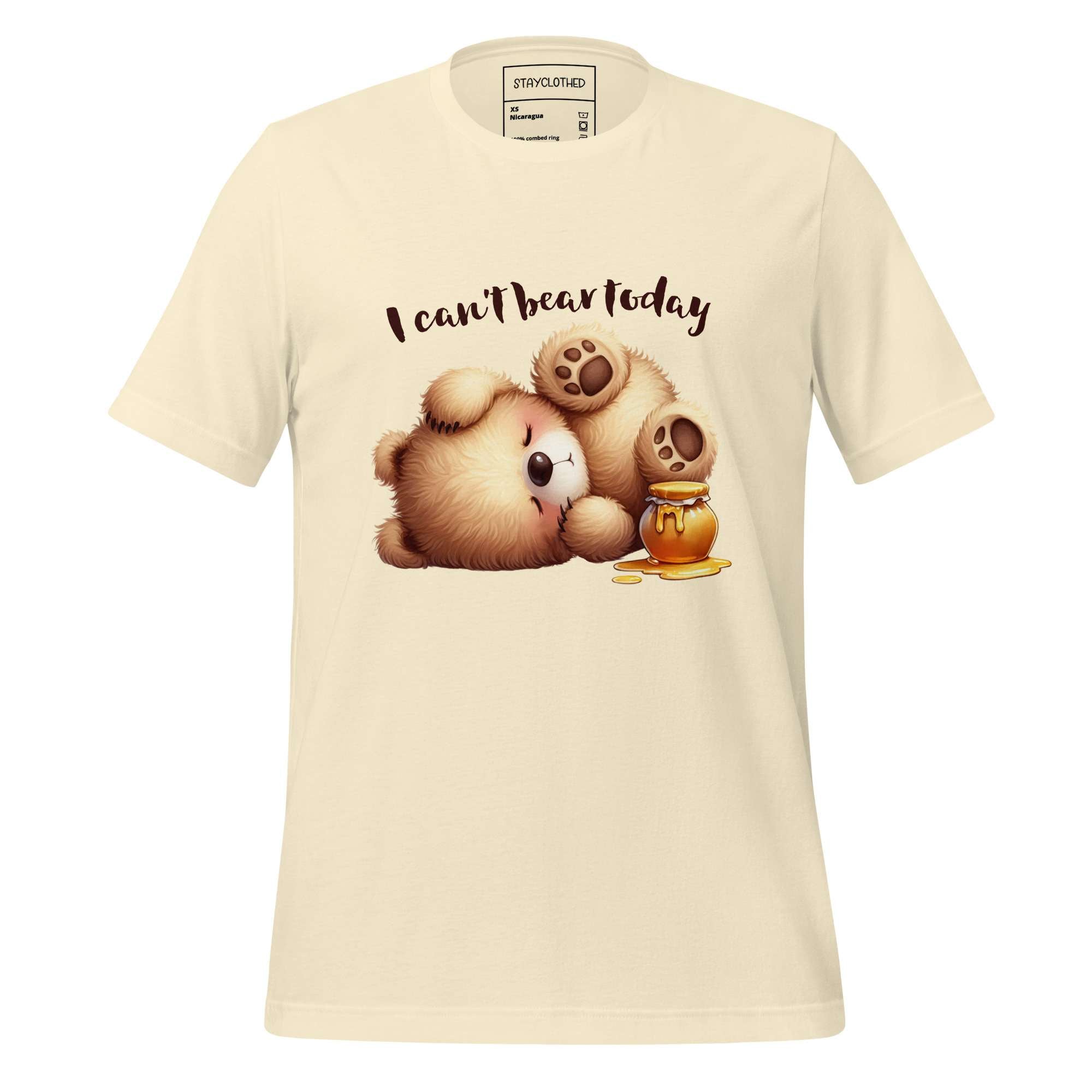 Beige t-shirt with a bear and honeycomb graphic and text 'I can't bear today' on a wooden surface, with 'StayClothed' branding.