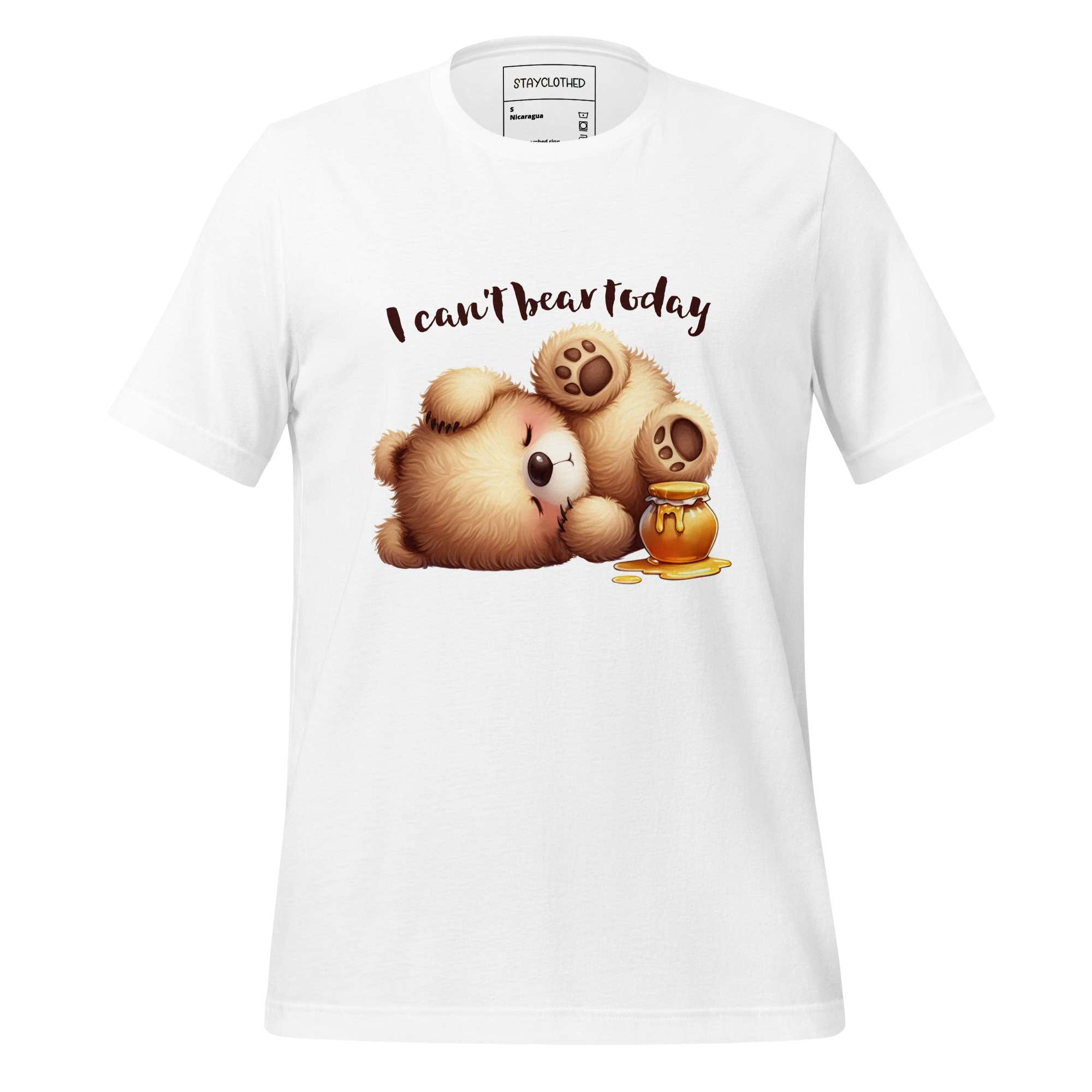 White t-shirt with teddy bear graphic and text 'I can't bear today' on a wooden surface, featuring the brand 'StayClothed'.