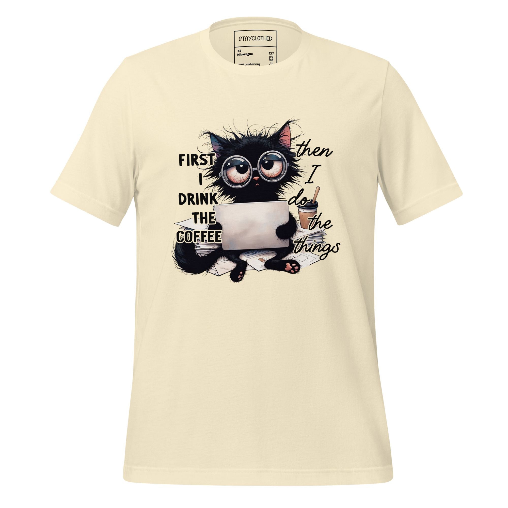 Beige t-shirt with a black cat graphic and text on a wooden surface, featuring the brand 'StayClothed'.