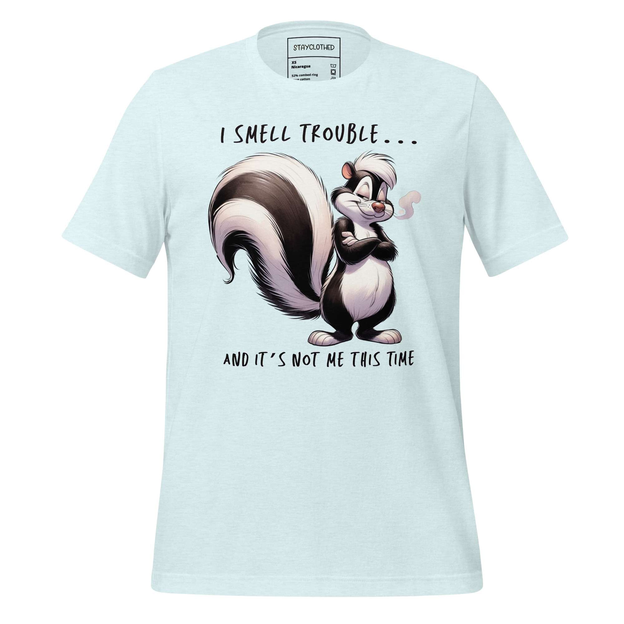 White t-shirt with cartoon skunk design and text on a wooden surface, featuring the brand 'StayClothed'.