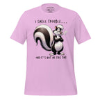 Pink t-shirt with a cartoon skunk design and text on a wooden surface, featuring the brand 'StayClothed'.