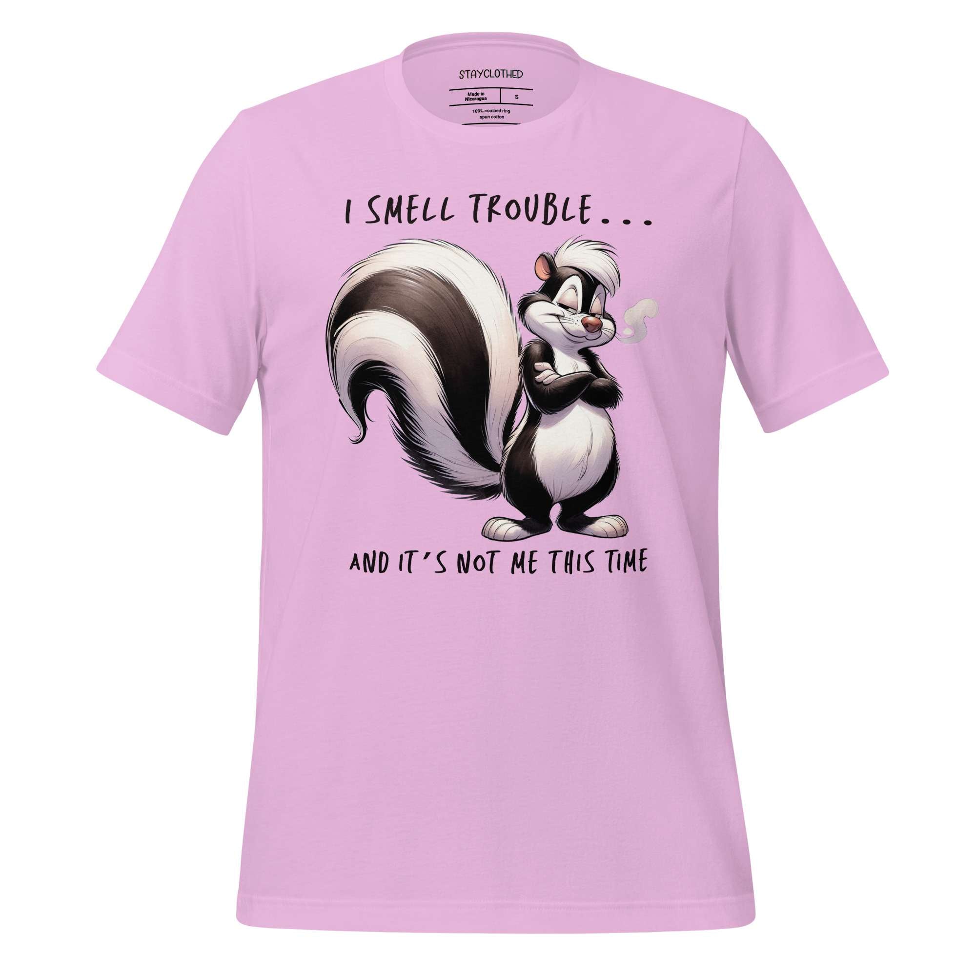 Pink t-shirt with a cartoon skunk design and text on a wooden surface, featuring the brand 'StayClothed'.