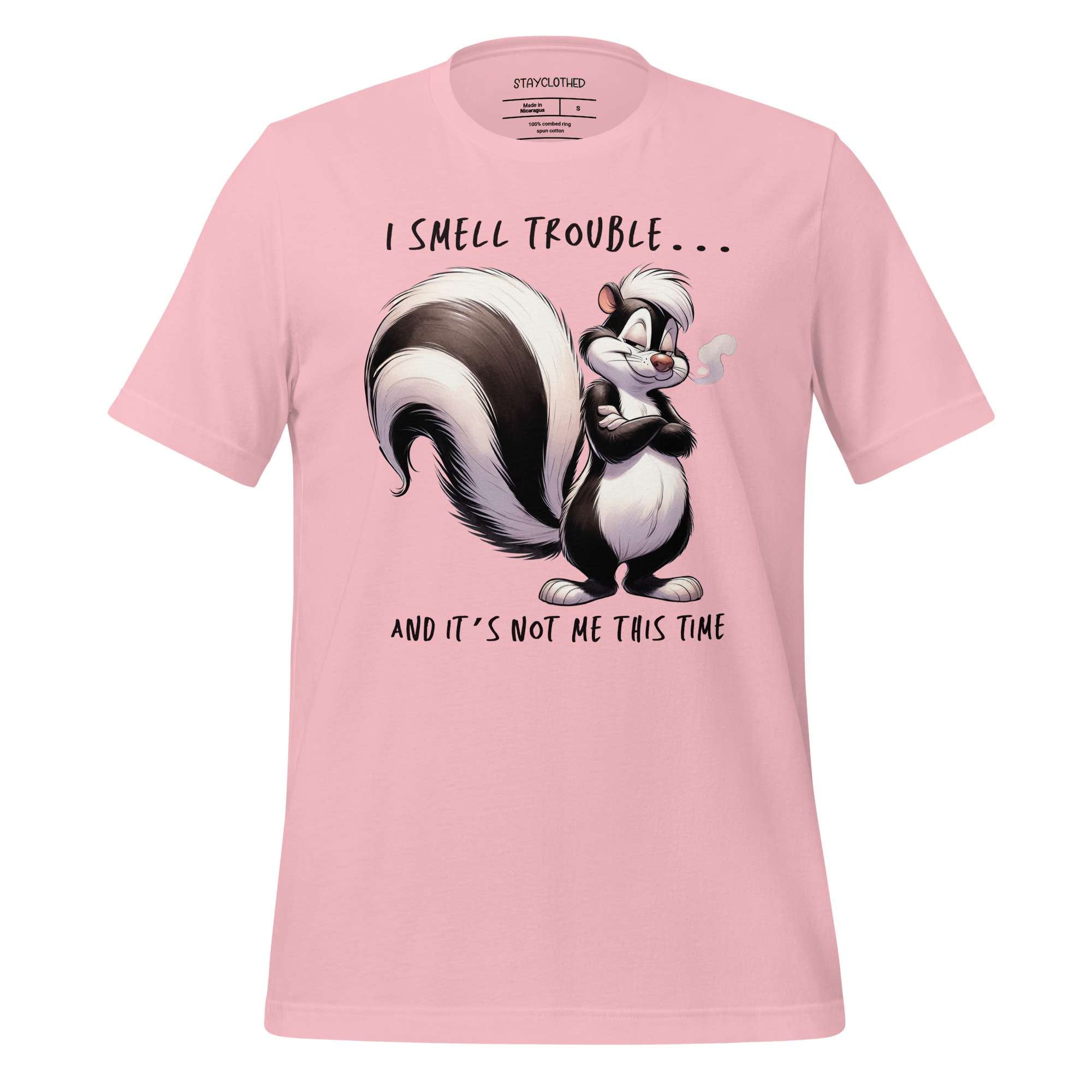Pink t-shirt with cartoon skunk design and text on a wooden surface, featuring the brand 'StayClothed'.
