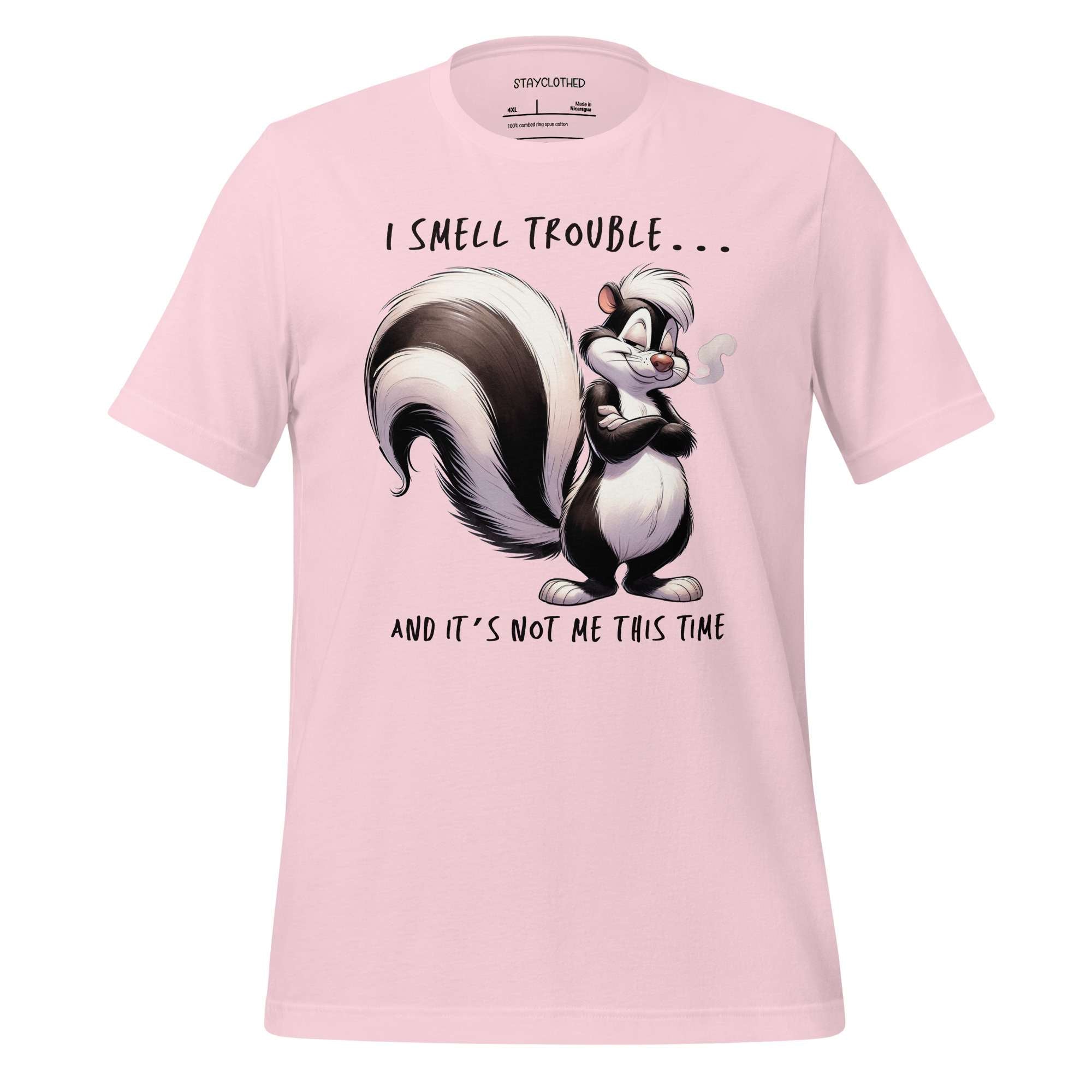 Pink t-shirt with a cartoon skunk design and text on a wooden surface, featuring the brand 'StayClothed'.