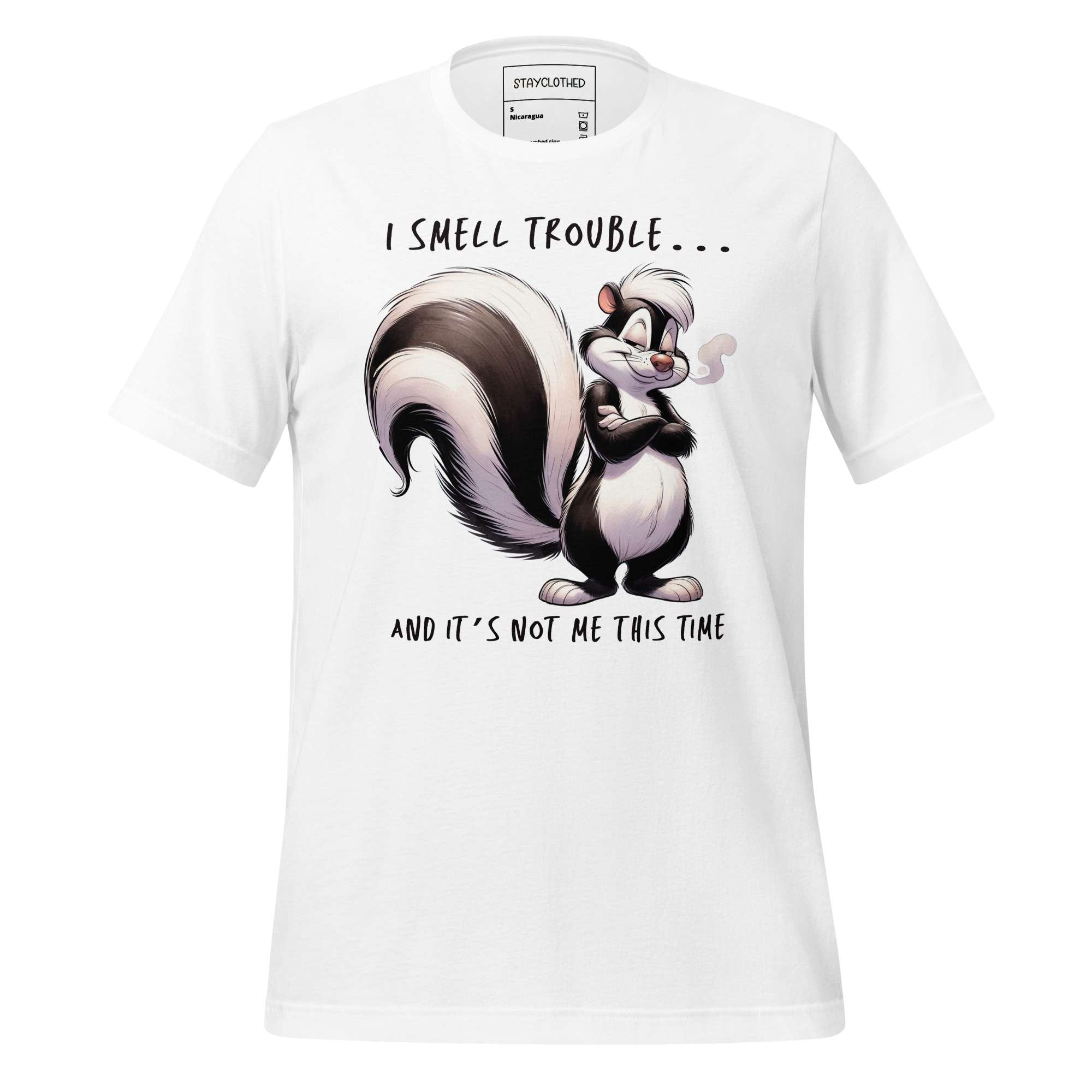 White t-shirt with cartoon skunk design and text on a wooden surface, featuring 'StayClothed' brand.