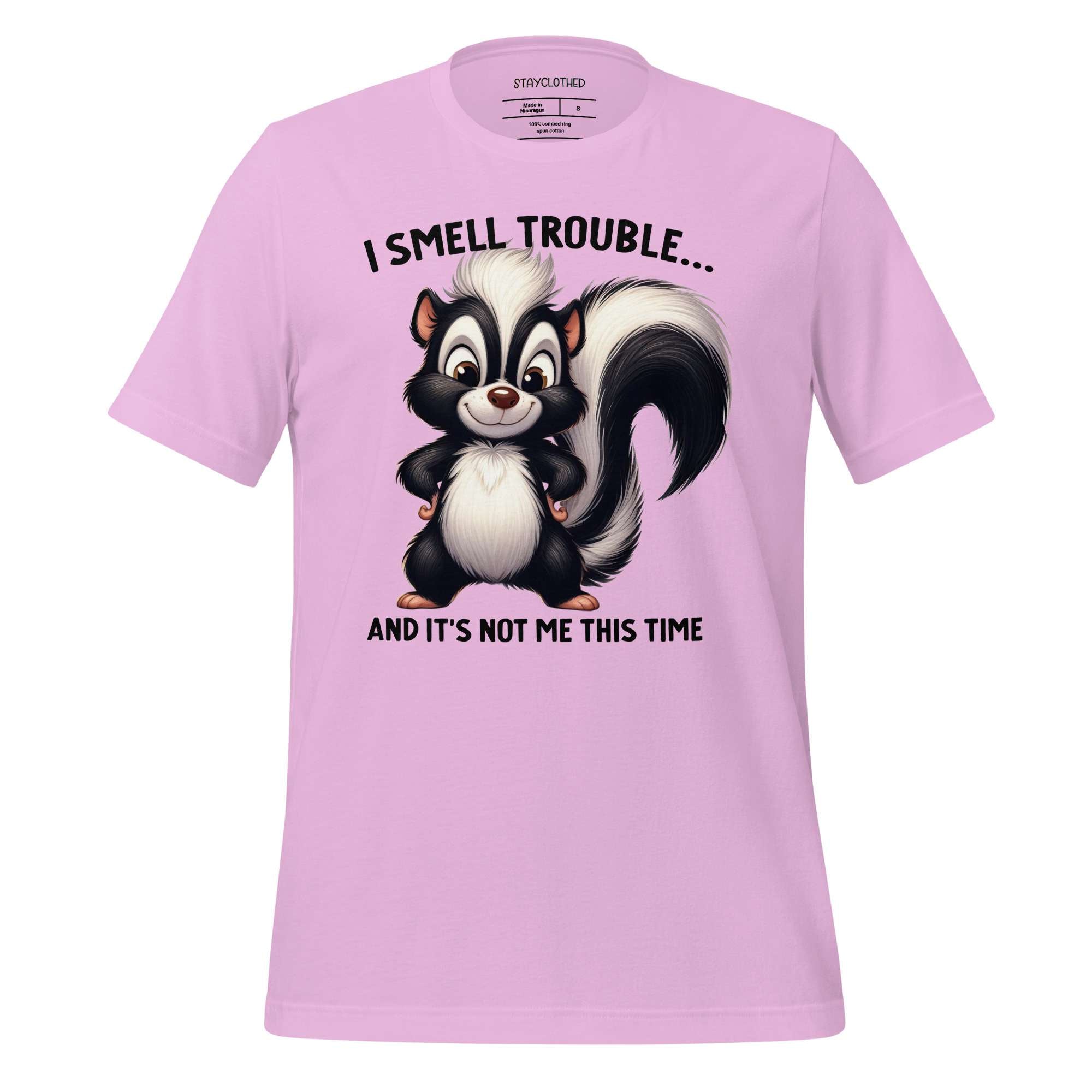 Pink t-shirt with a cartoon skunk design and text on a wooden surface, featuring the brand 'StayClothed'.