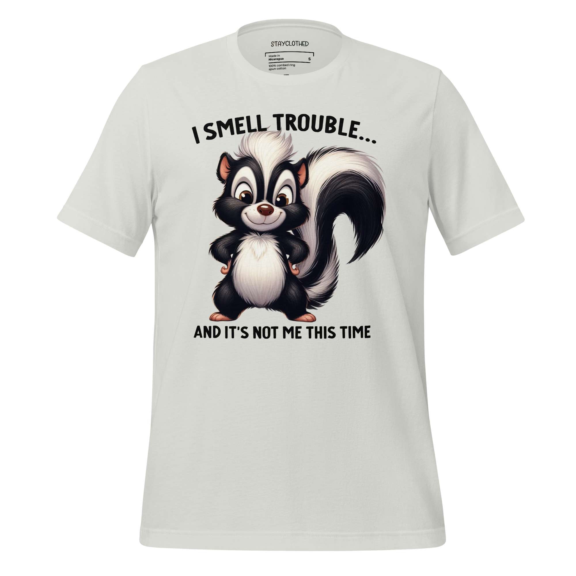 White t-shirt with cartoon skunk design and text on a wooden surface