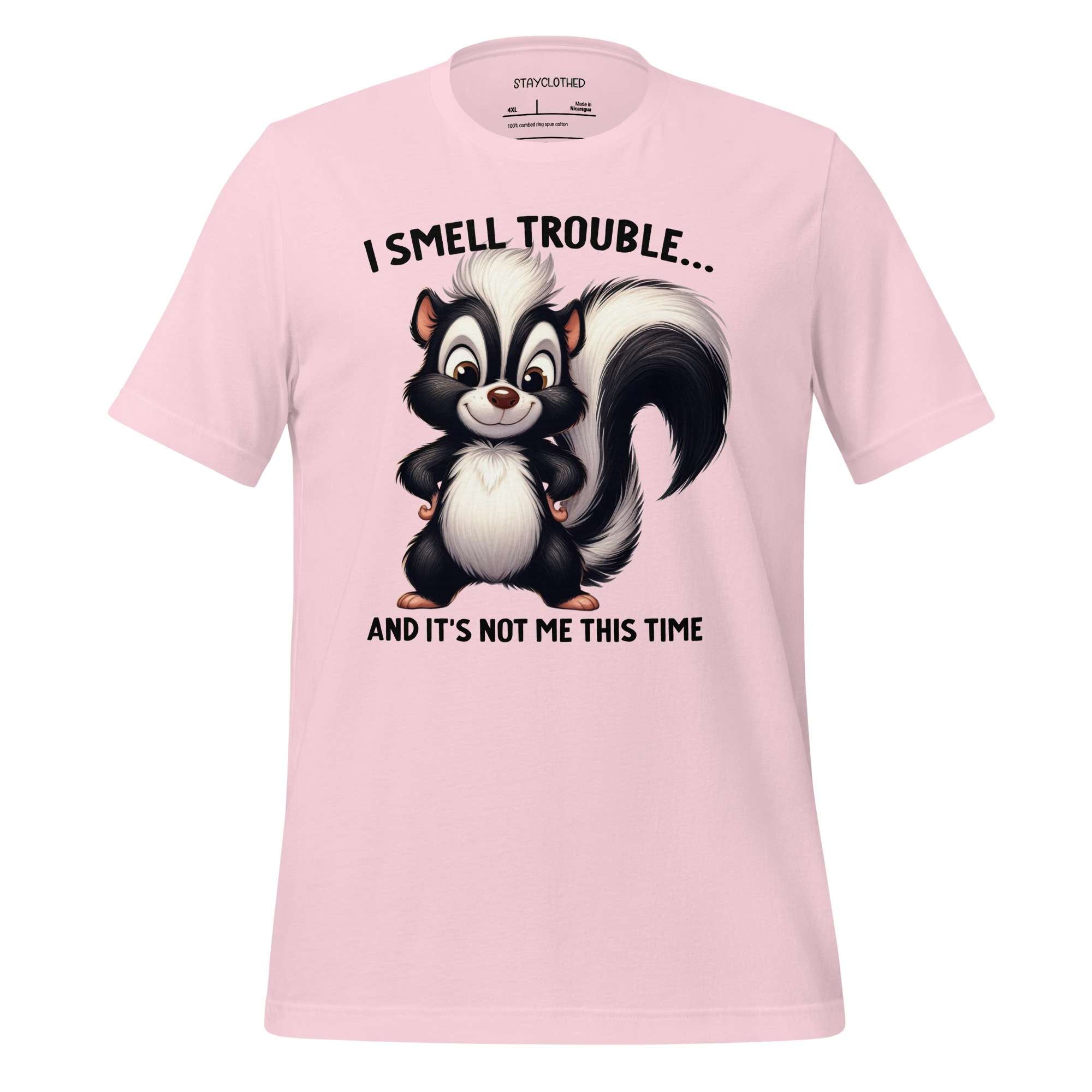 Pink t-shirt with a cartoon skunk graphic and text on a wooden surface, featuring the brand 'StayClothed'.