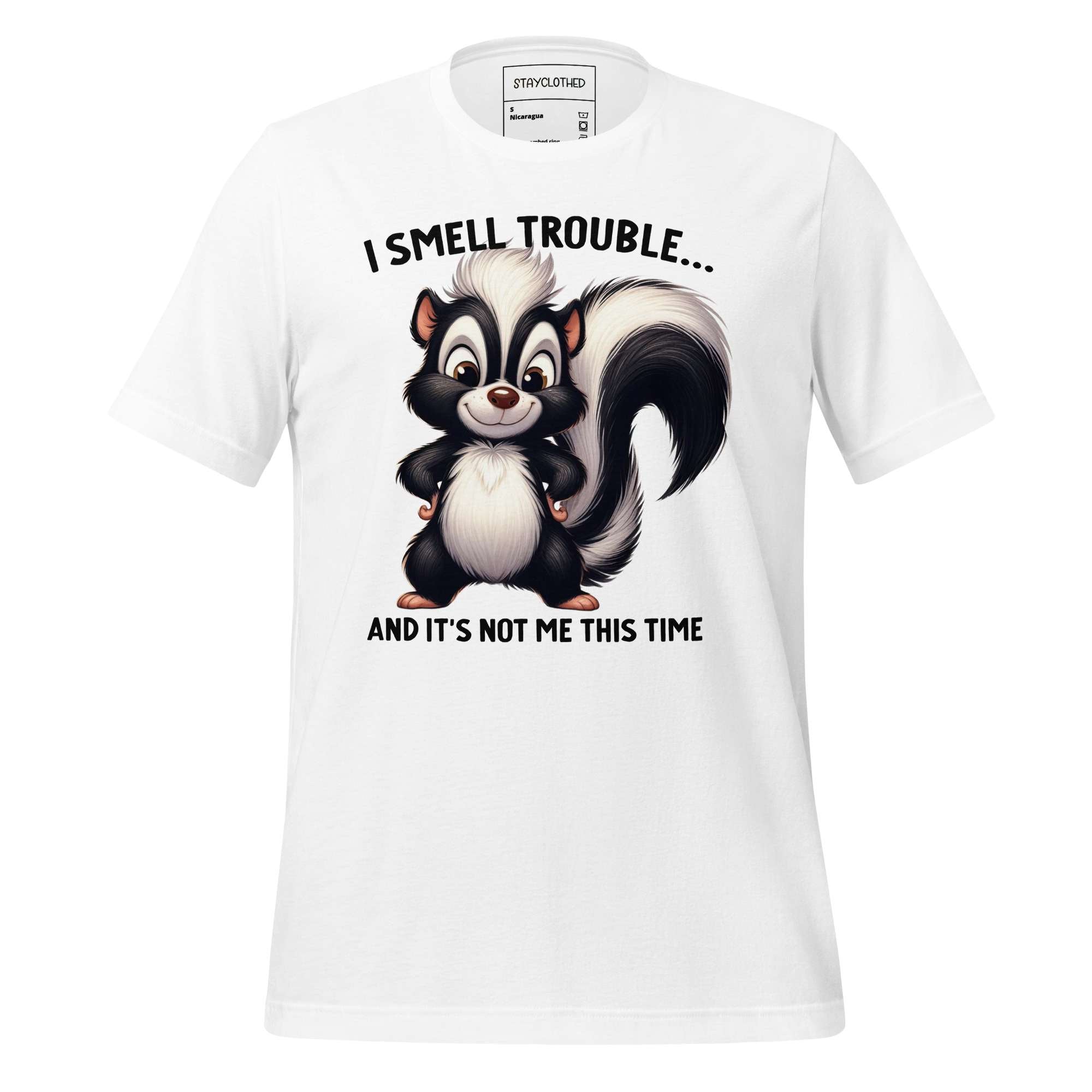 White t-shirt with cartoon skunk graphic and text on a wooden surface, featuring the brand 'StayClothed'.