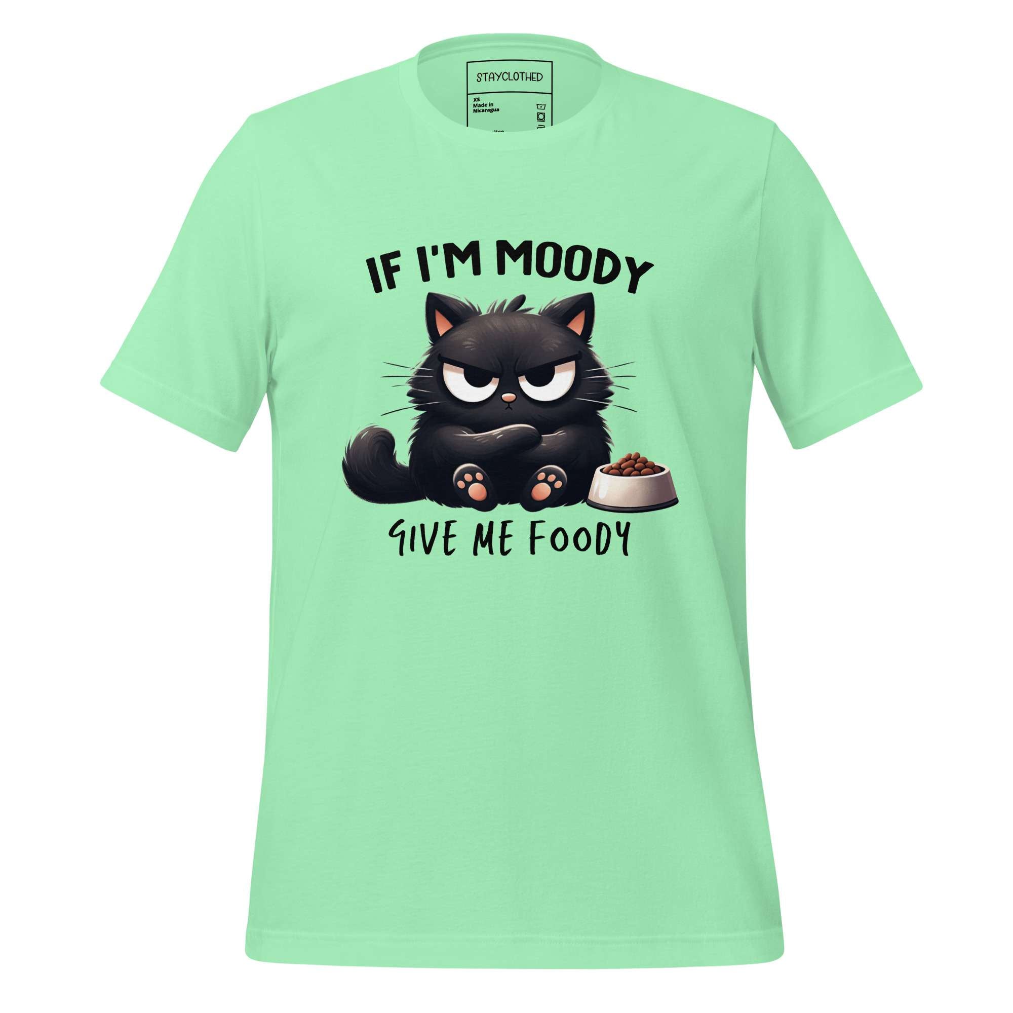 Light green t-shirt with a black cat graphic and text on a wooden surface, featuring the brand 'StayClothed'.