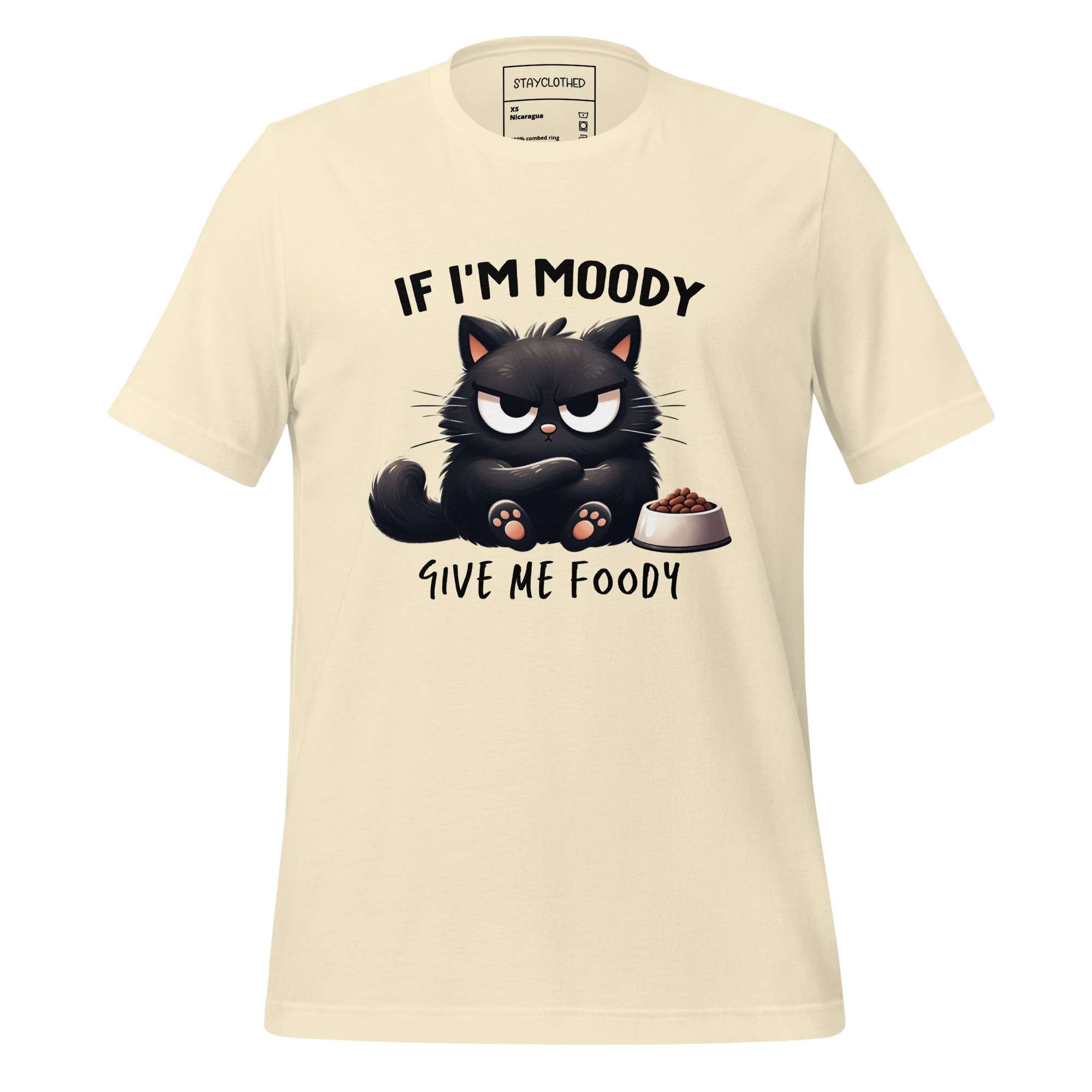 Beige t-shirt with a cat graphic and text on a wooden surface, featuring the brand 'StayClothed'.