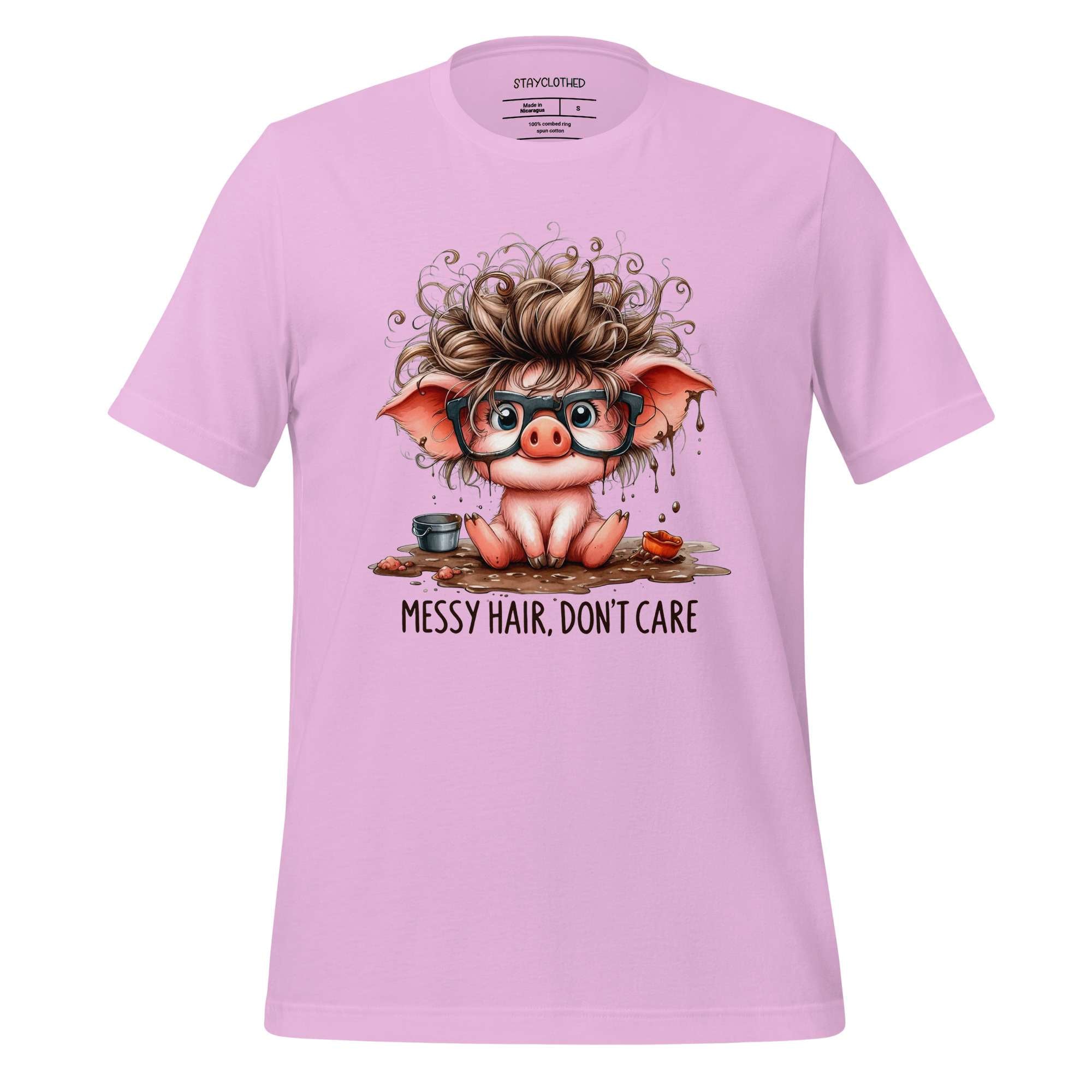 Pink t-shirt with a cartoon pig design and 'Messy Hair, Don't Care' text on a wooden surface.
