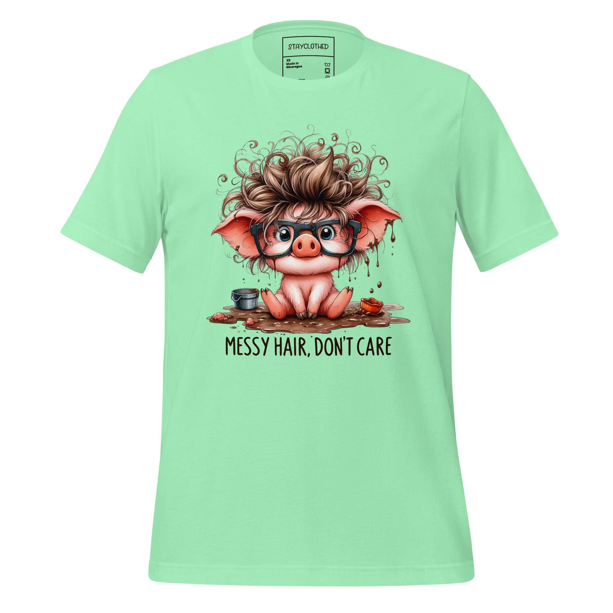 Light green t-shirt with a cartoon pig design and 'StayClothed' branding on a wooden surface.