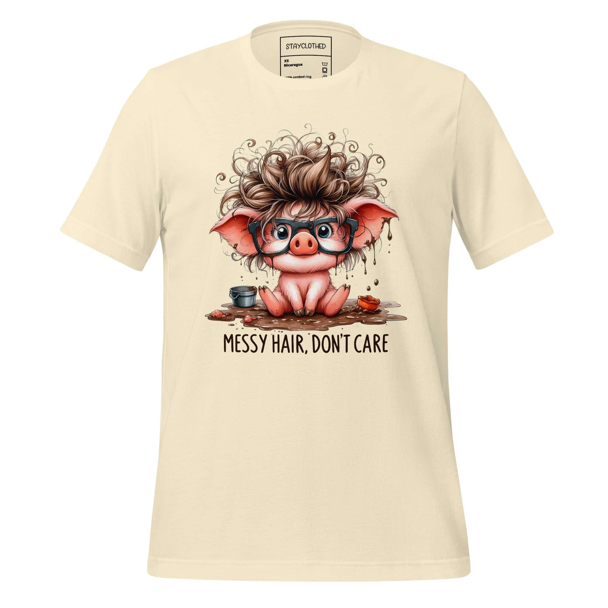 Beige t-shirt with a cartoon pig design and 'Messy Hair, Don't Care' text on a wooden surface.