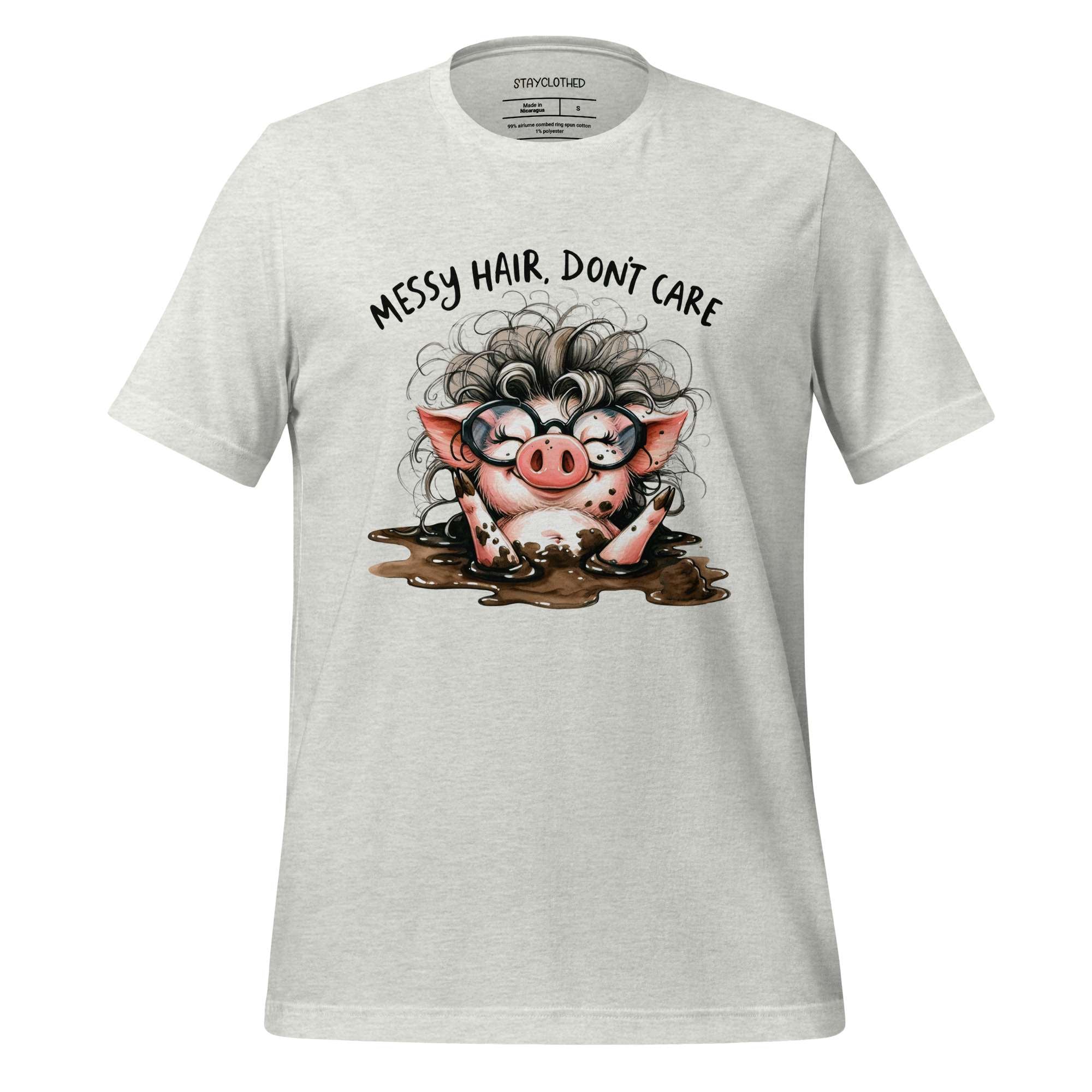 White t-shirt with a cartoon pig design and text 'Messy hair, don't care' on a wooden surface.