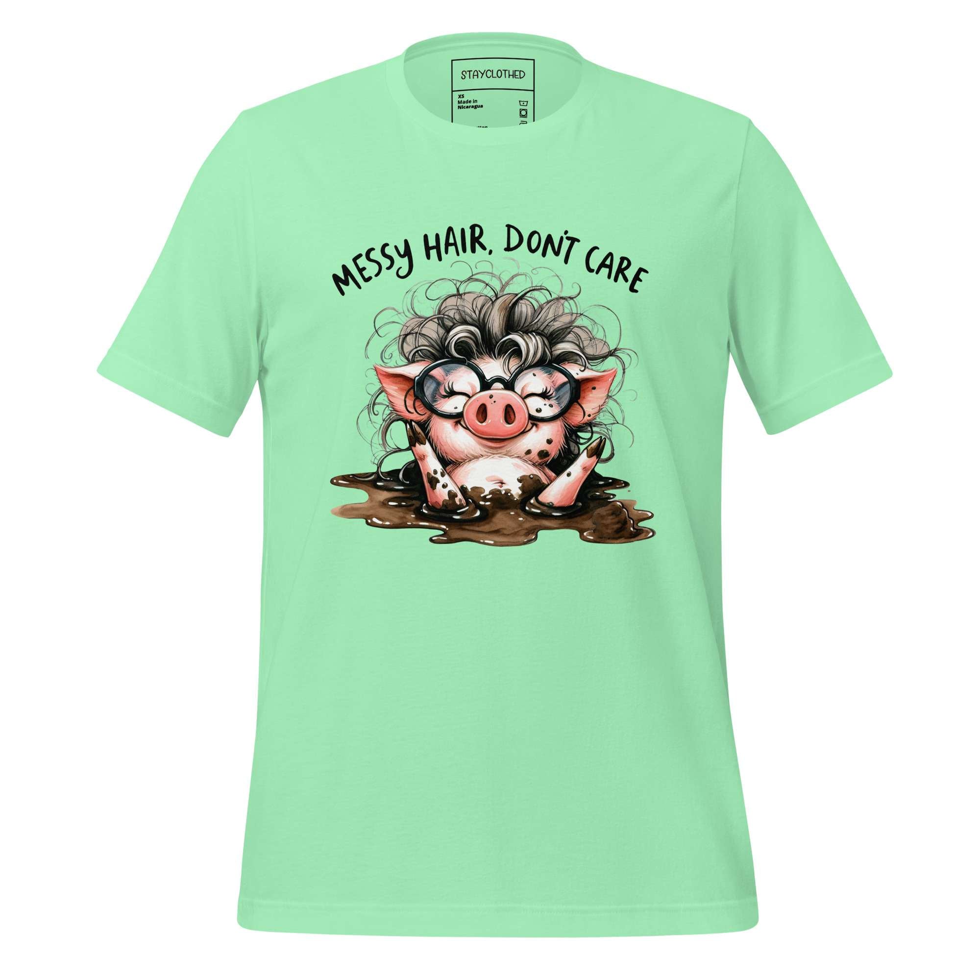 Mint green t-shirt with a cartoon pig design and text on a wooden surface, featuring the brand 'StayClothed'.