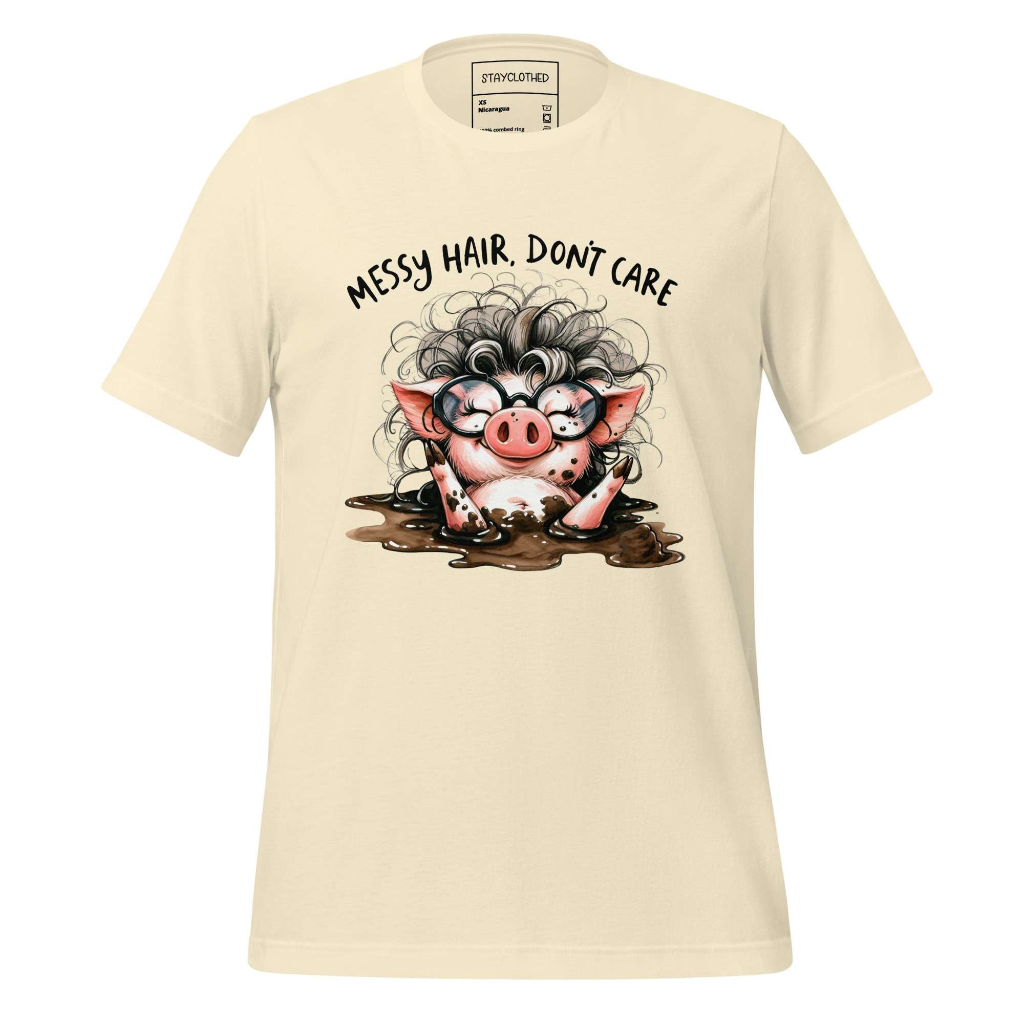 Beige t-shirt with a cartoon pig design and text 'Messy hair, don't care' on a wooden surface.
