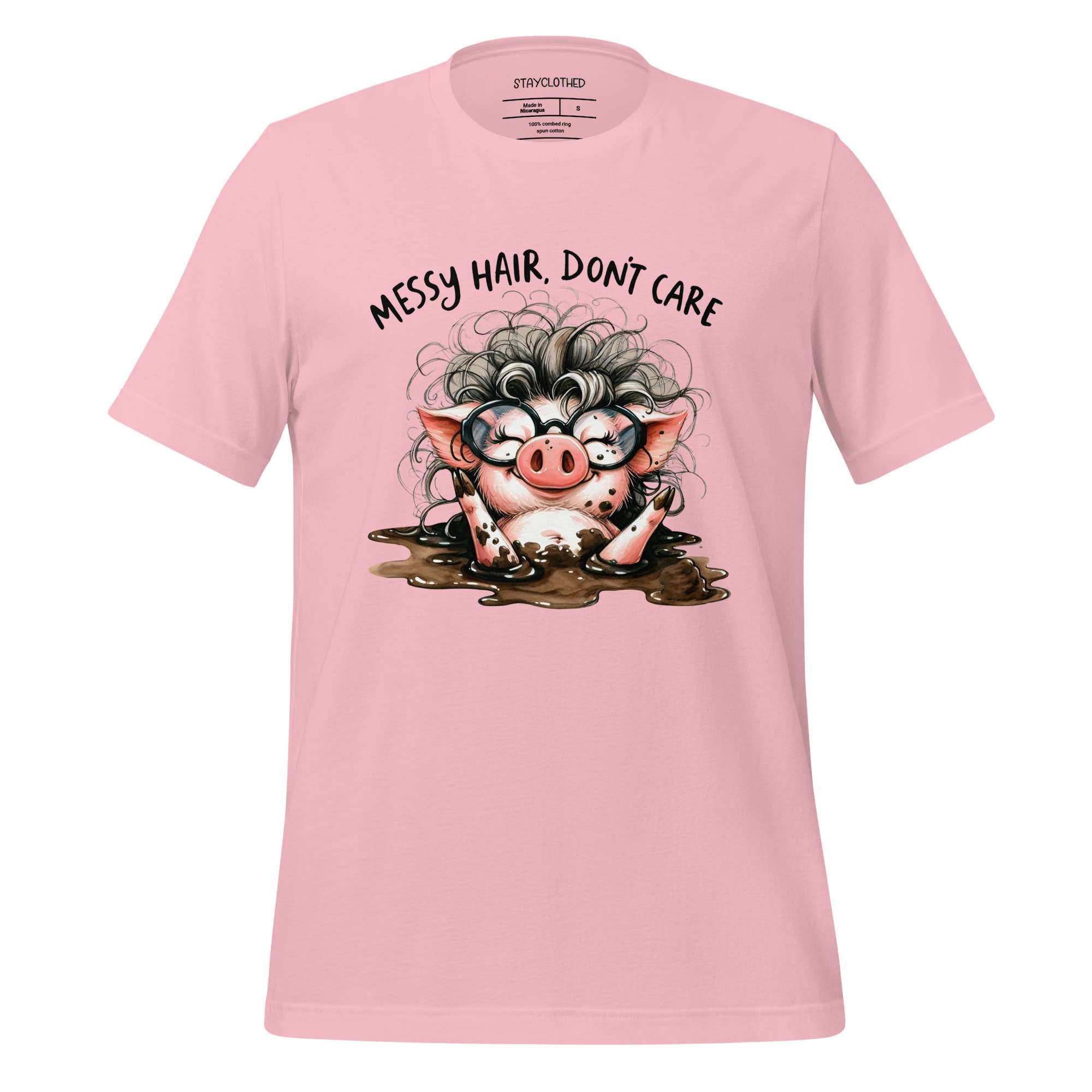 Pink t-shirt with a cartoon pig design and text 'Messy hair, don't care' on a wooden surface.