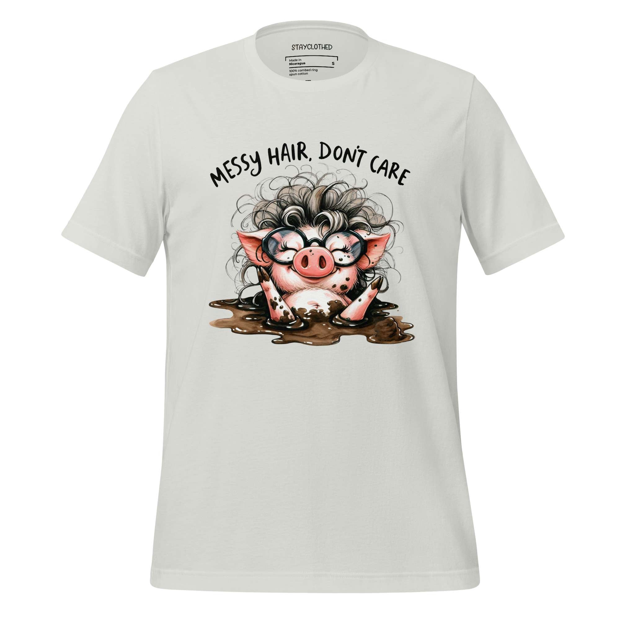 White t-shirt with a cartoon pig design and text 'Messy hair, don't care' on a wooden surface.