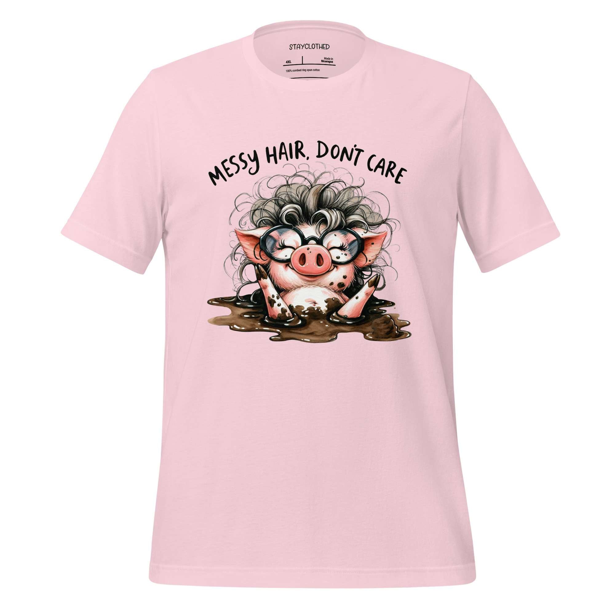 Pink t-shirt with a cartoon pig design and text 'Messy hair, don't care' on a wooden surface.