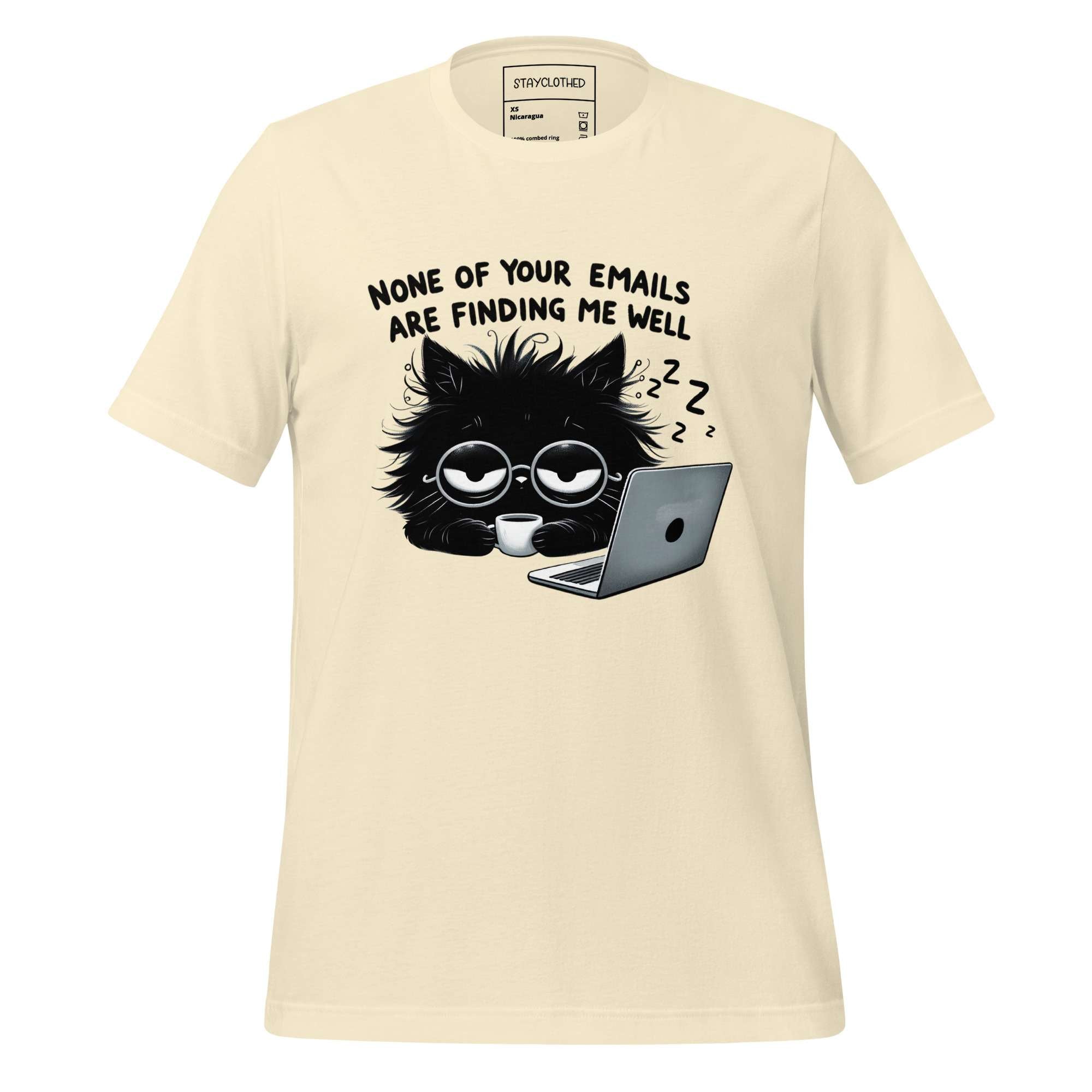 Beige t-shirt with a black cat graphic and text on a wooden surface, featuring the brand 'StayClothed'.