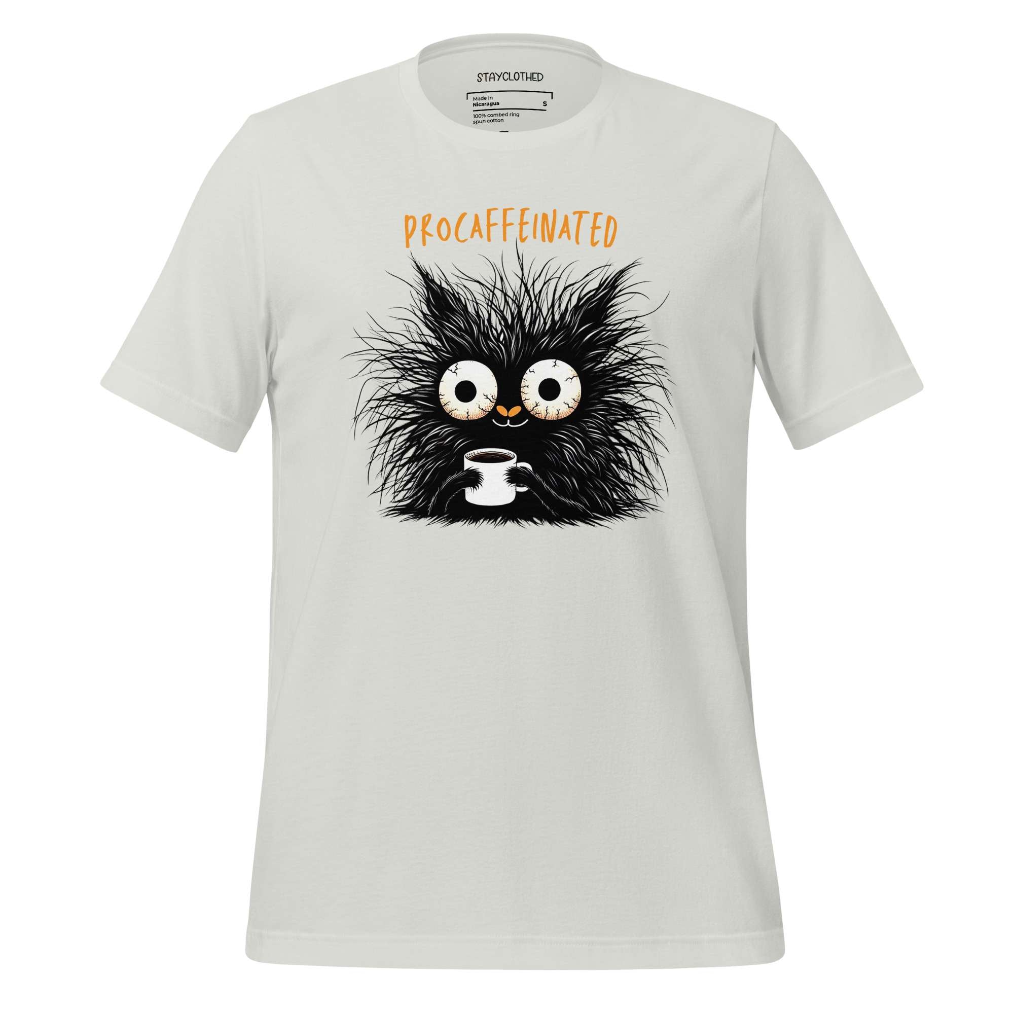 White t-shirt with a cartoon cat holding a coffee cup on a wooden surface, featuring the brand 'StayClothed'.